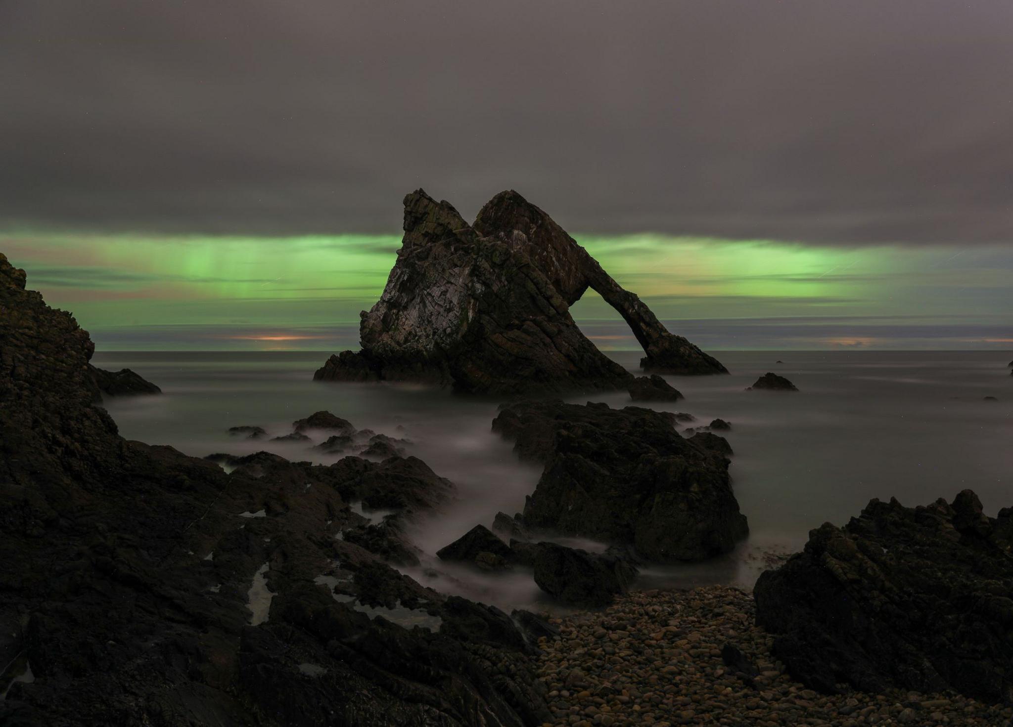 Green tinged northern lights over water