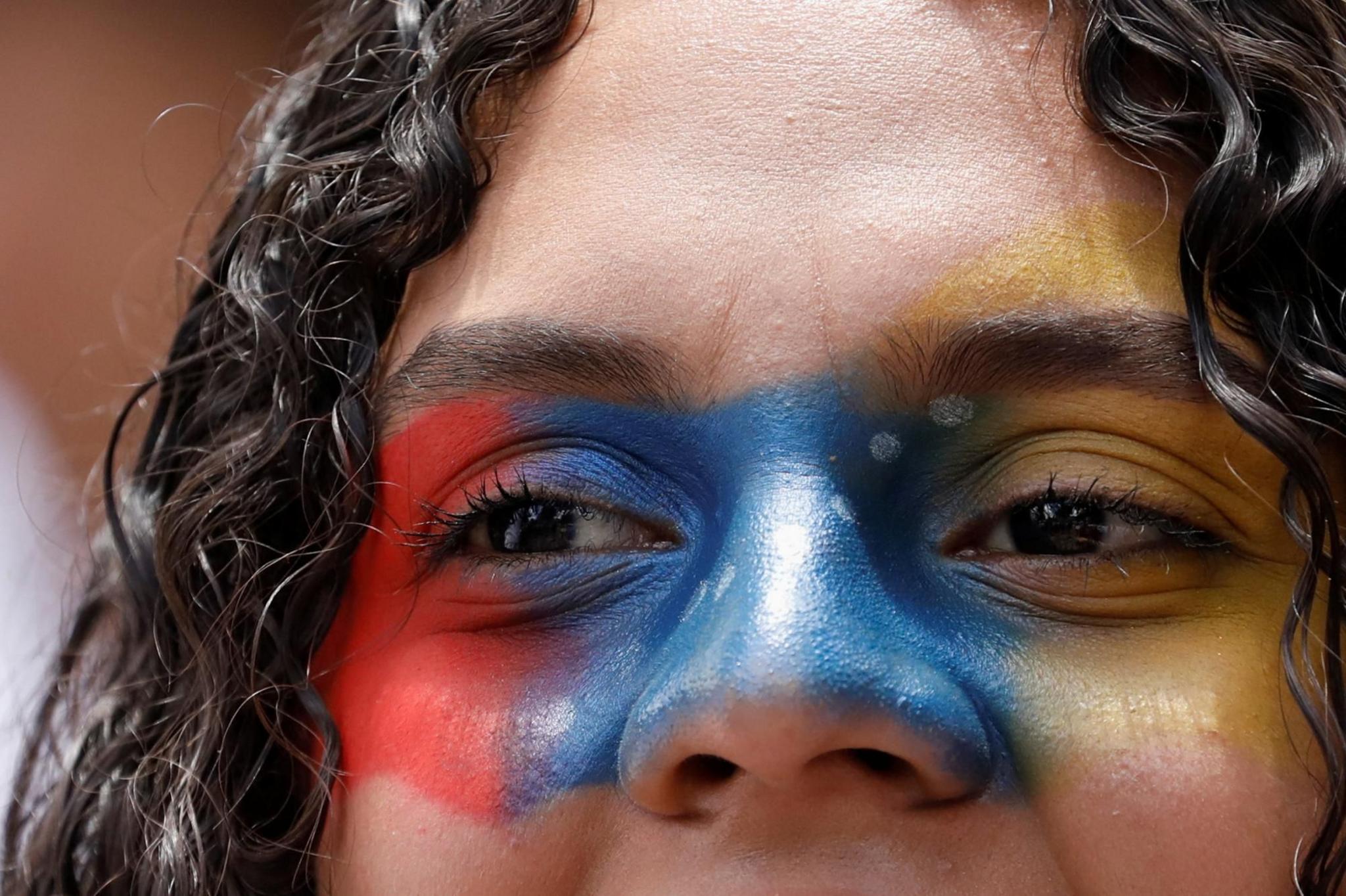 A demonstrator with face paint looks on during a protest against election results