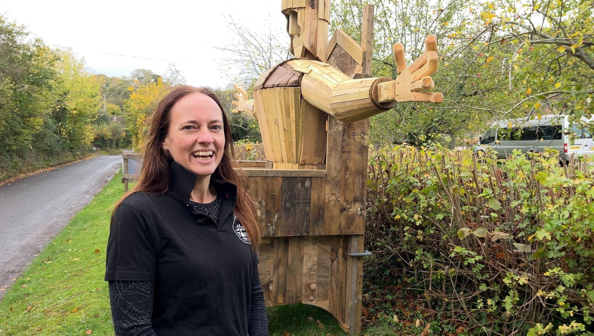 Gemma standing by the Torm Man structure outside of Torre Cider Farm on an overcast day.