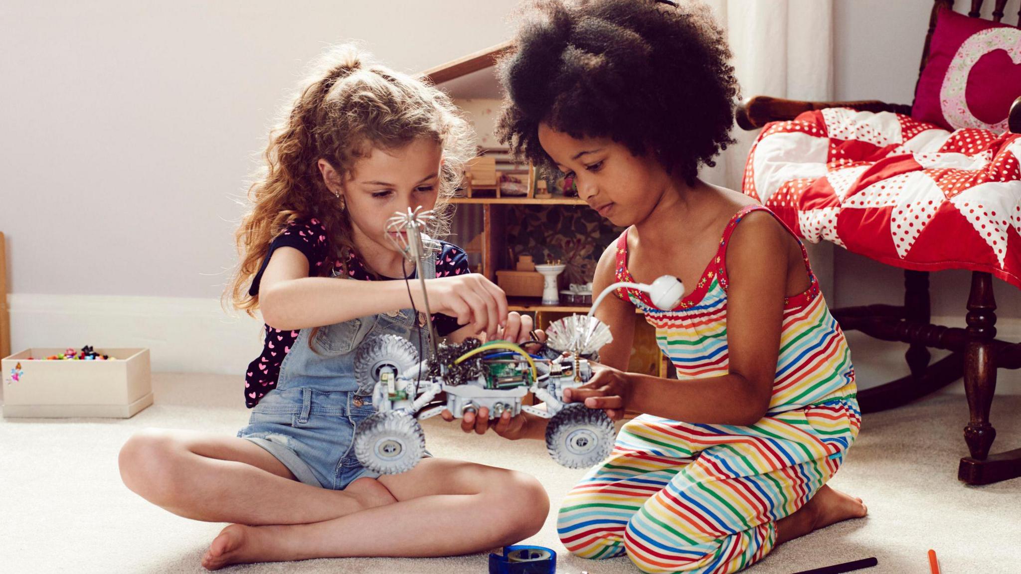 Two girls playing with a toy car.