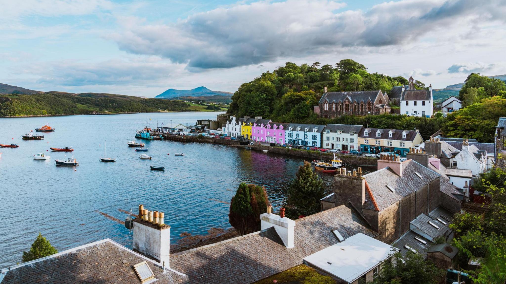 A row of colourful houses by a fishing pier with boats in the bay.