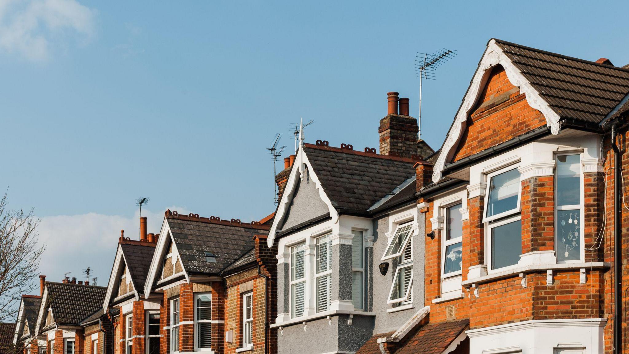 A row of brick houses with triangular roofs on a sunny day.