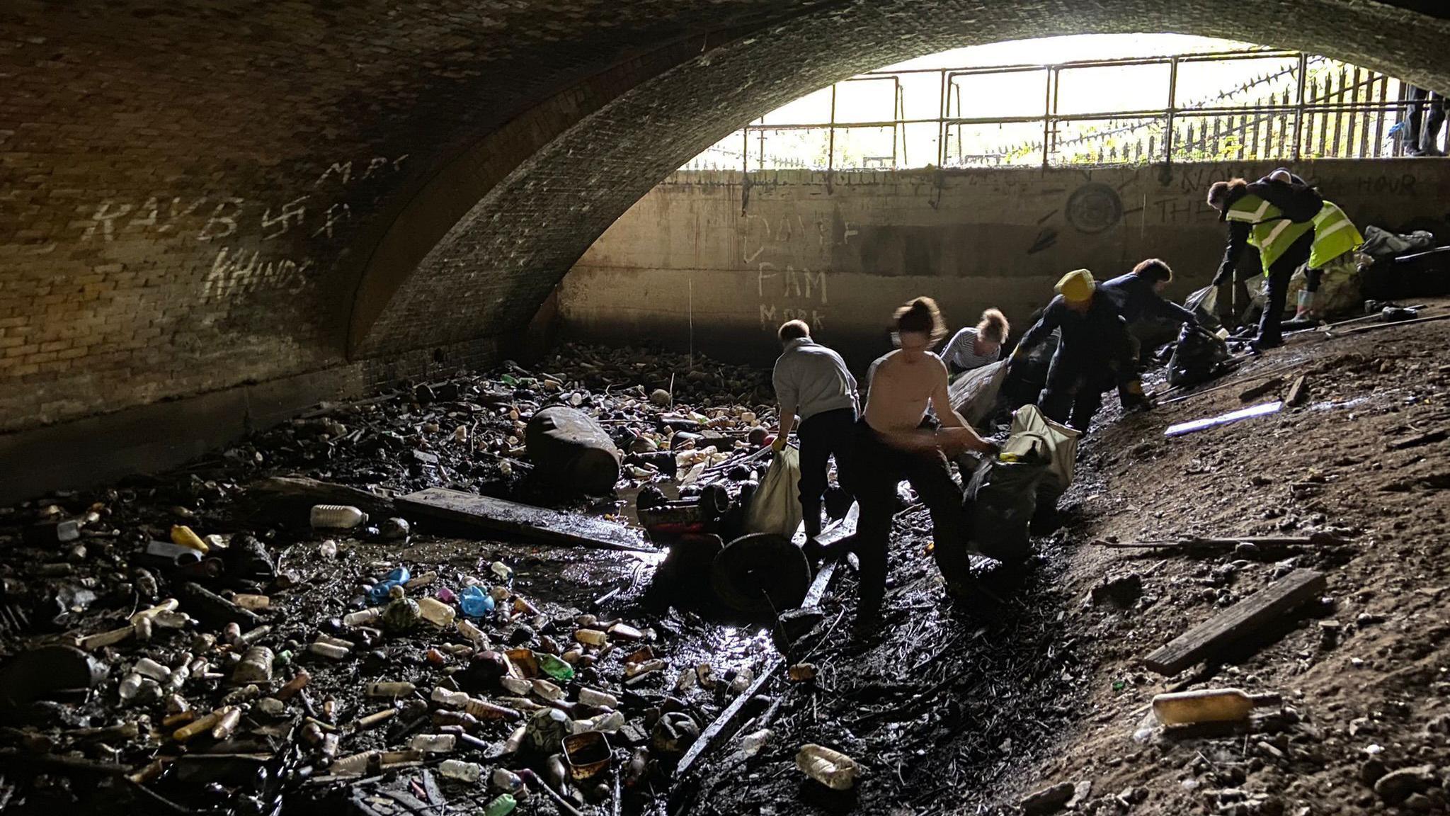 People are in a dark tunnel picking up rubbish