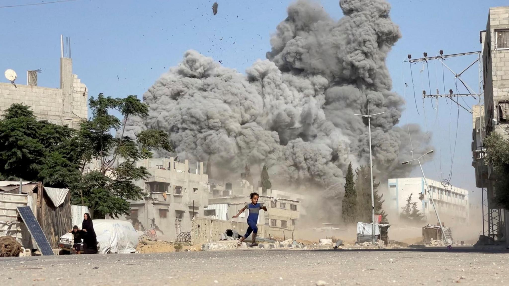 A girl runs after Israeli air strikes on a school sheltering displaced people in Bureij refugee camp, central Gaza (17 July 2025)