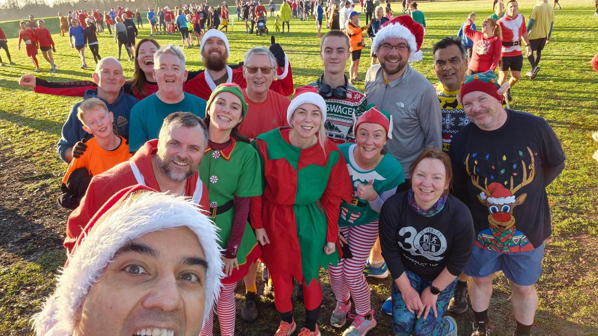 A group of people in festive outfits stood in a park smiling at the camera.