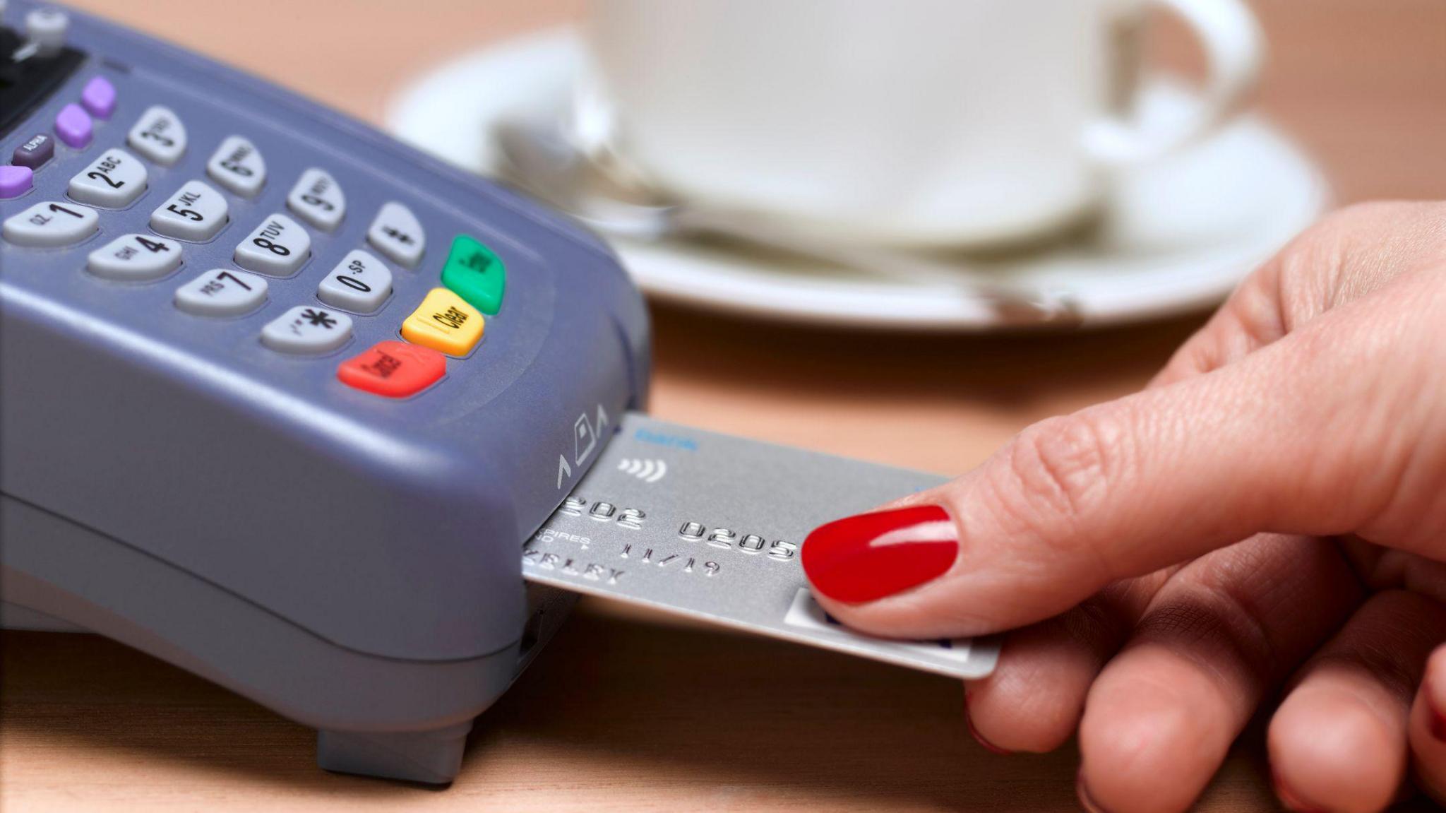 A person with red nails enters a pin when paying with a card on a machine