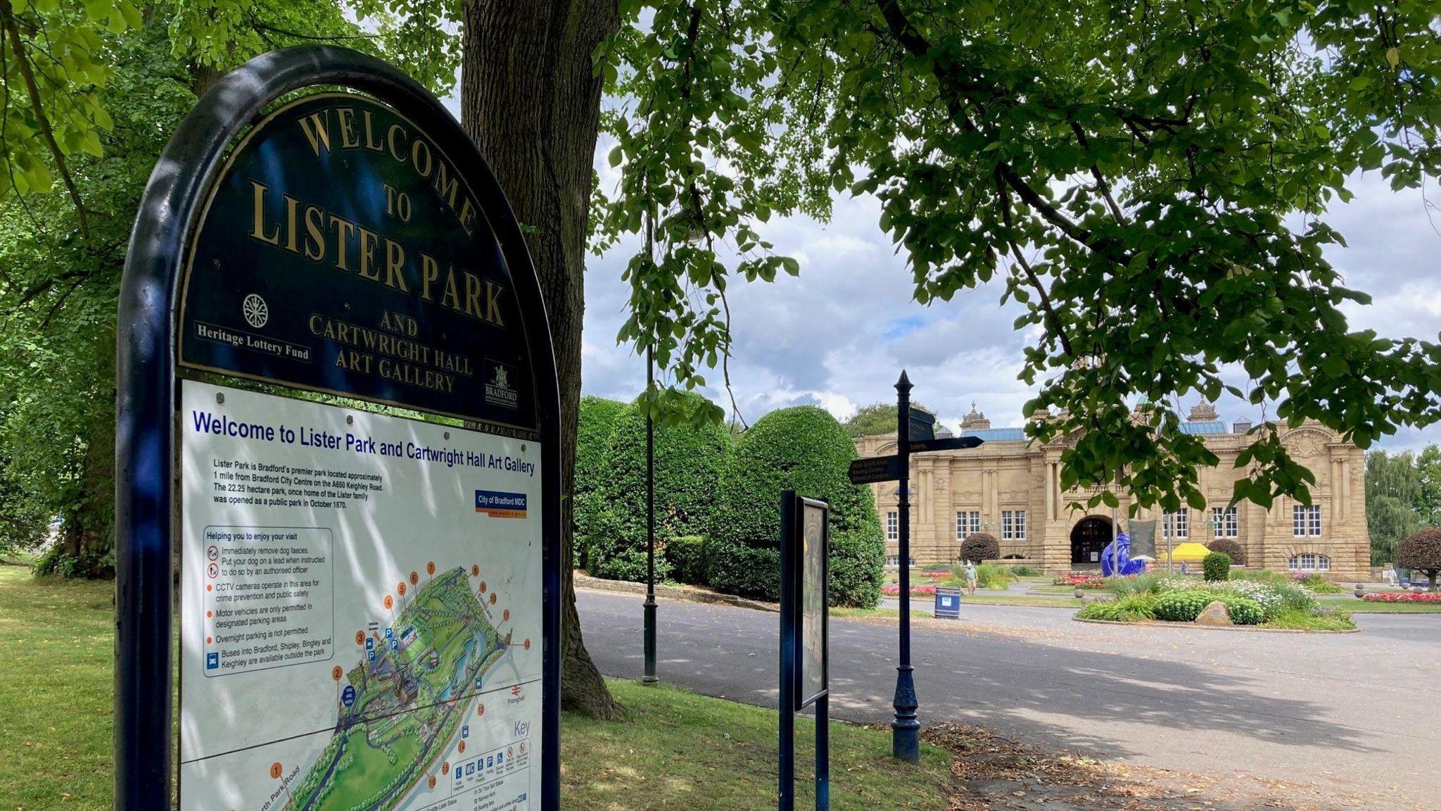 A blue metal sign with gold lettering in the foreground and a Yorkshire stone building in the background.