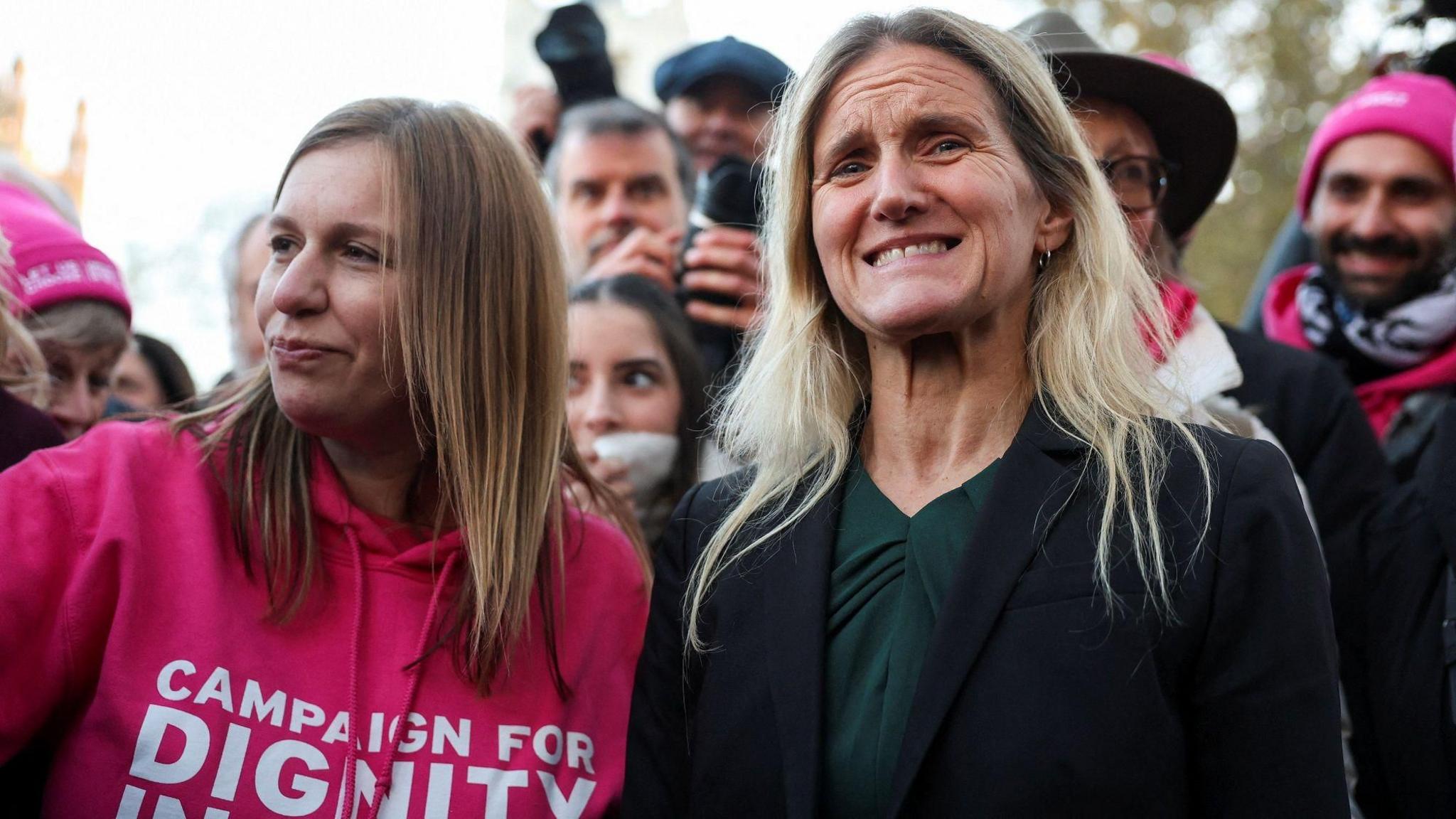 Kim Leadbeater, who has long blonde hair, a black suit jacket and forest green top, appears emotional as she stands next to campaigners outside Westminster.