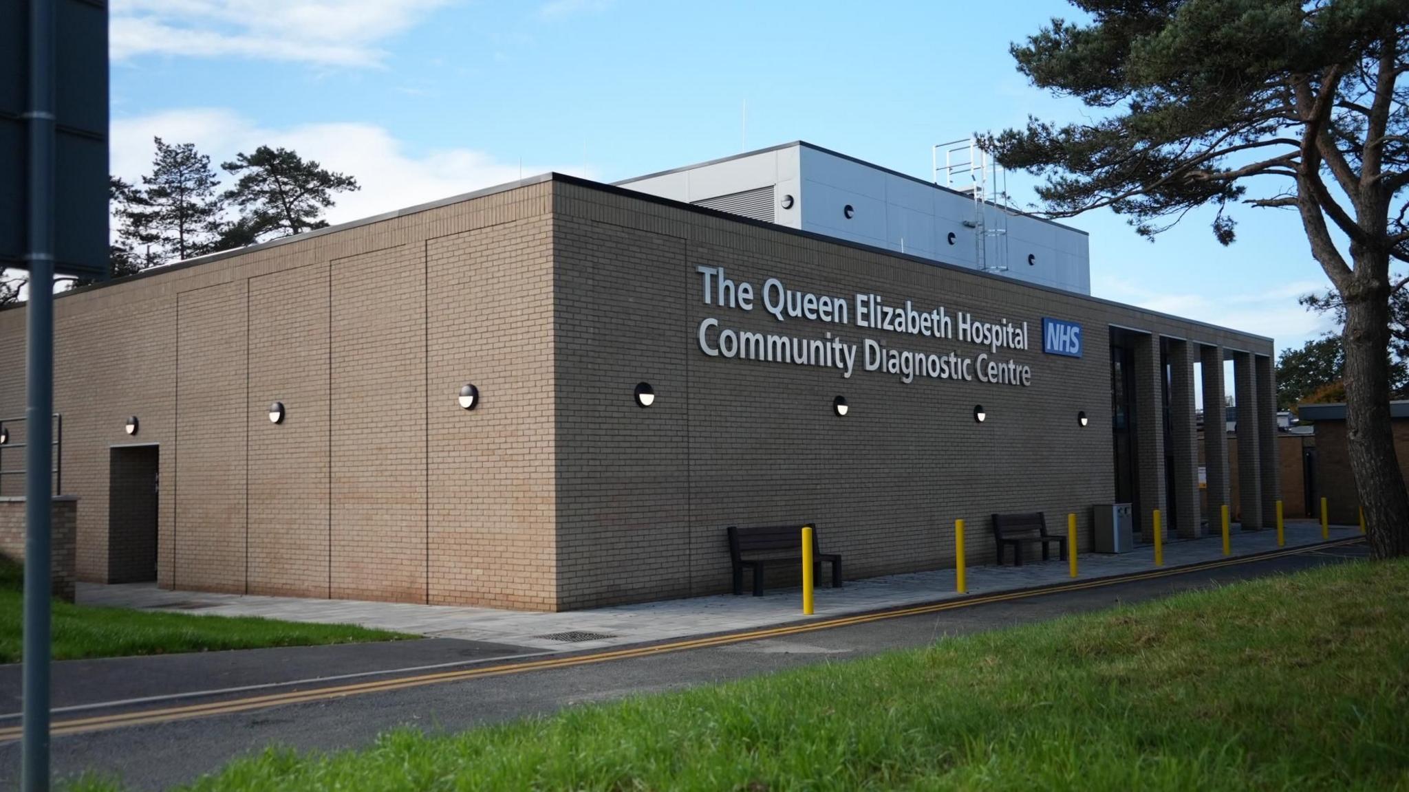 The outside of the Community Diagnostic Centre at the Queen Elizabeth Hospital. It shows a tan brick new building with signage on the front 