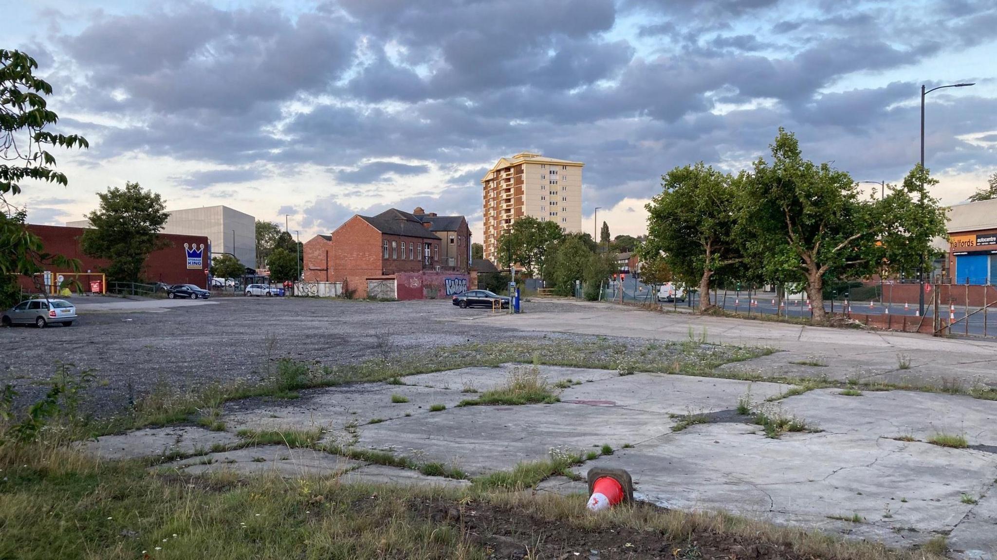 An outside shot of a car park with houses in the background 