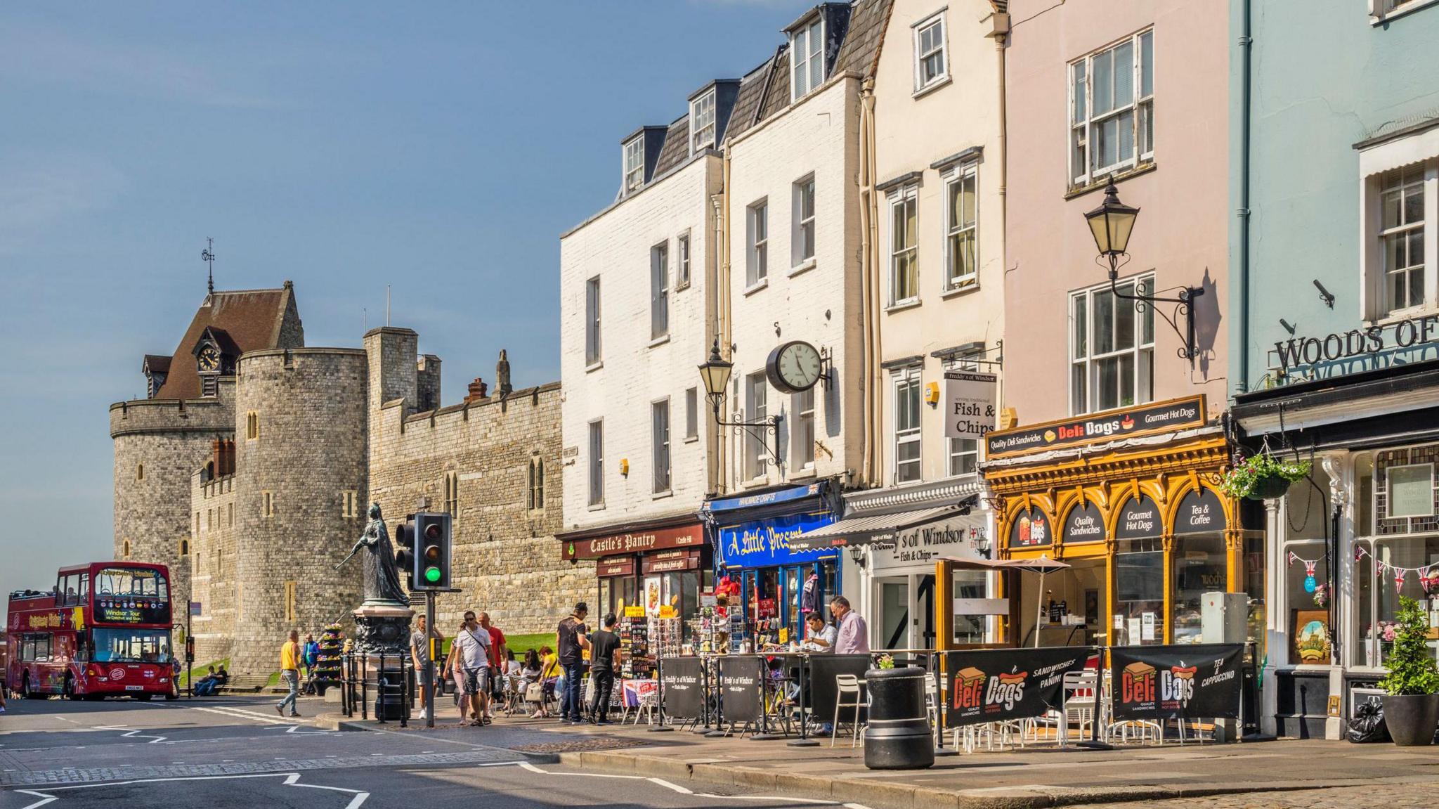 A general view of Windsor High Street with Queen Victoria statue and the Lower Ward of Windsor Castle with shoppers and pedestrians.