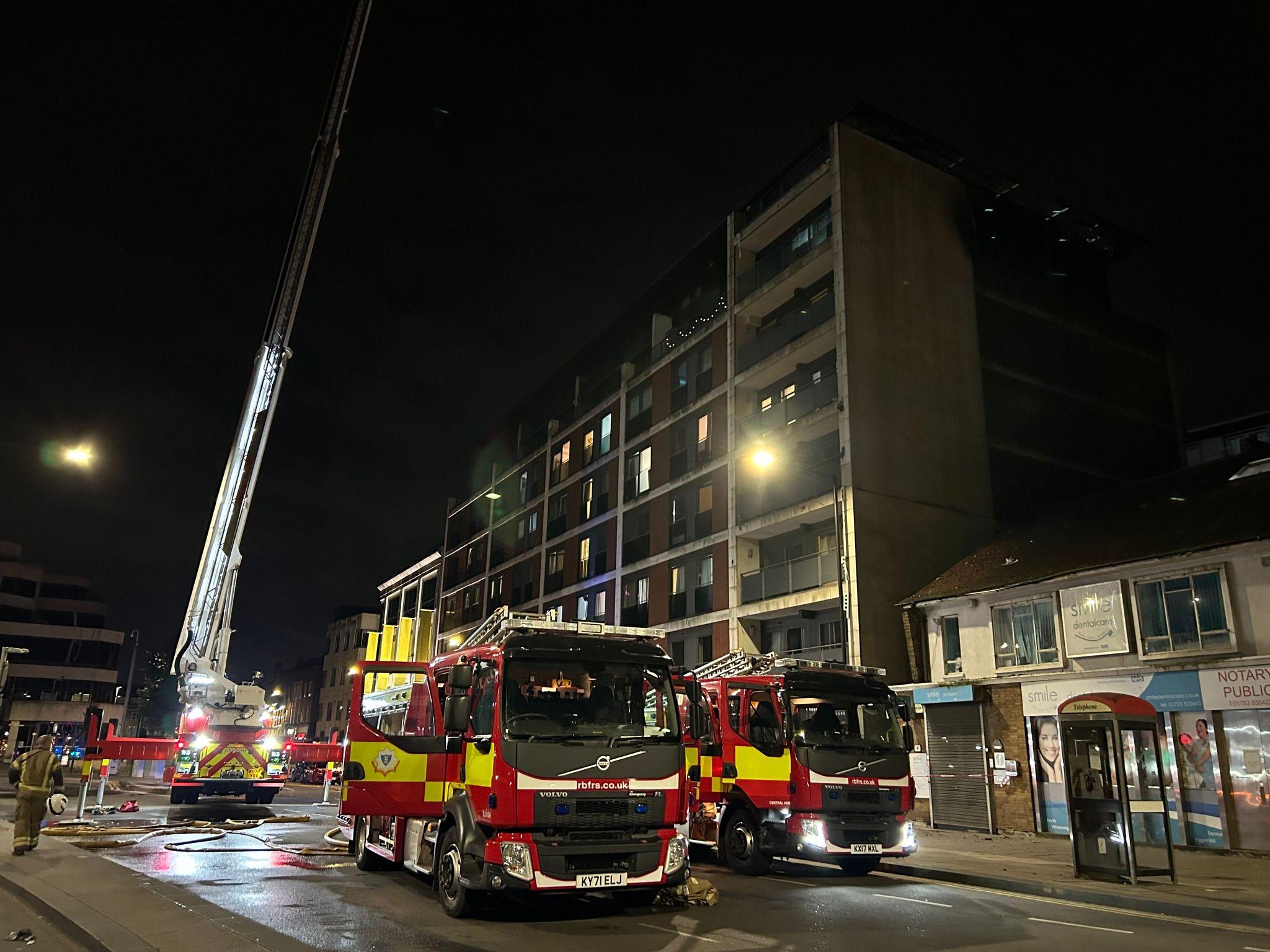 Three fire engines outside the Mosaic Apartments building Slough, with a tall platform elevated from a fire engine on the left of it 