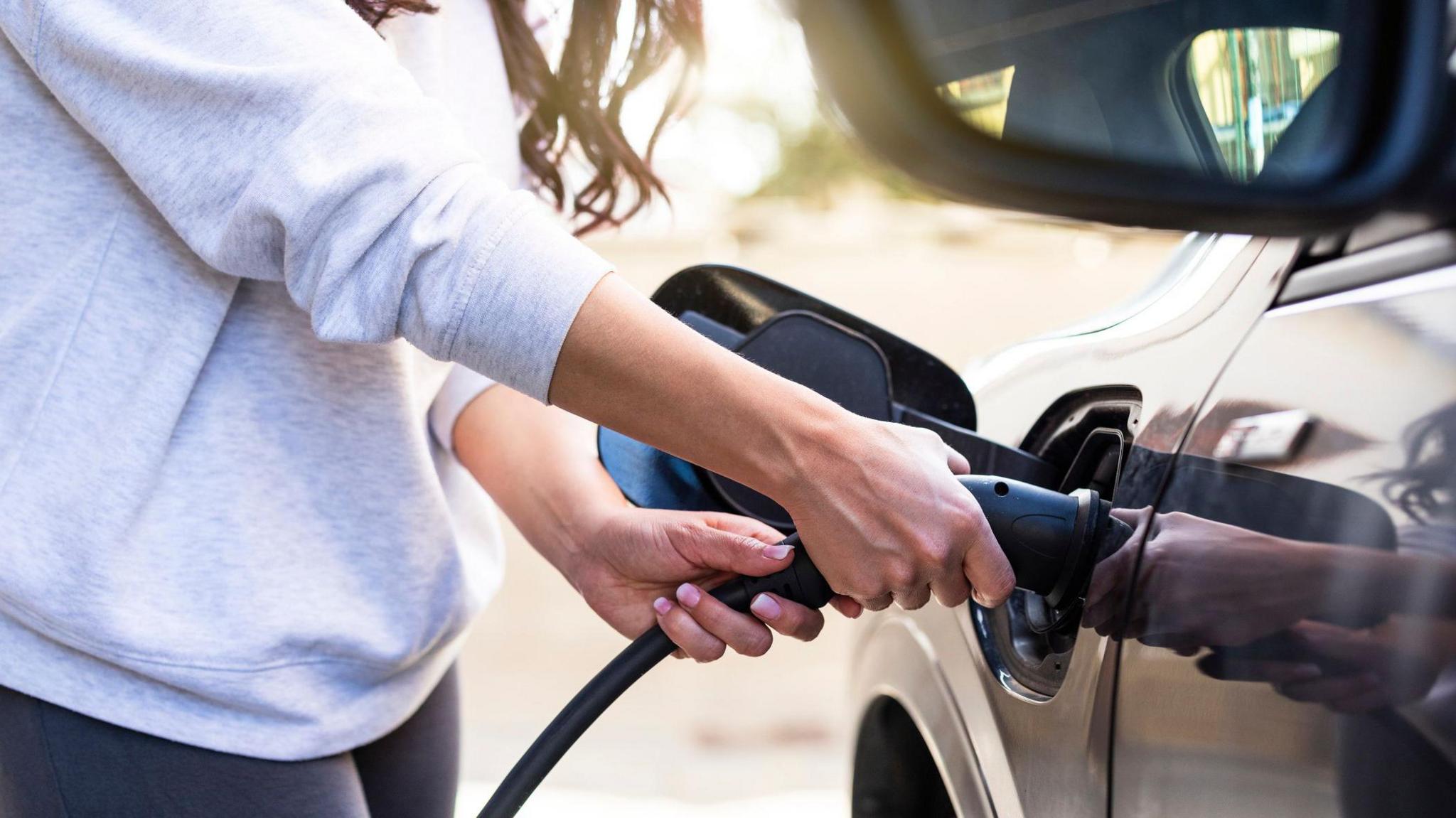 Woman charging electric car at station 