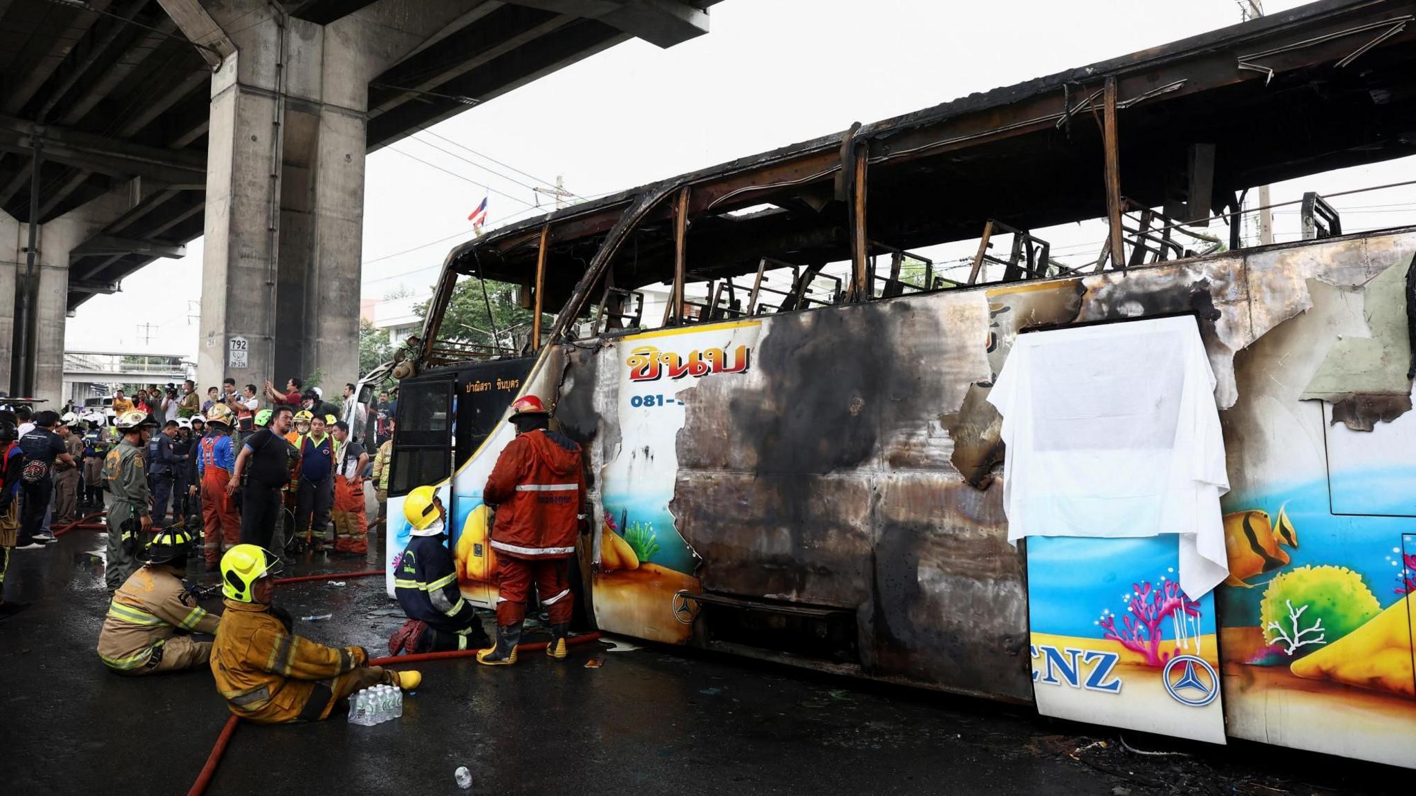 Firefighters work to extinguish a burned out school bus