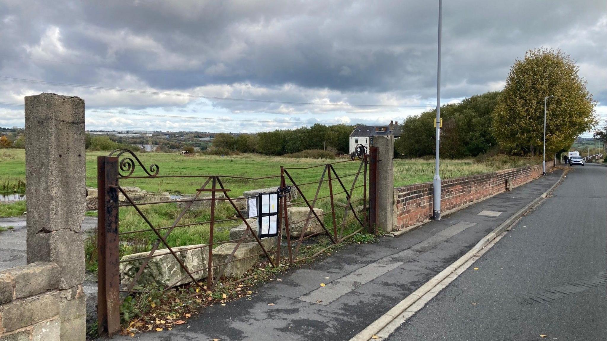 Stone pillars and bent rusting gates at the entrance to the disused quarry site.