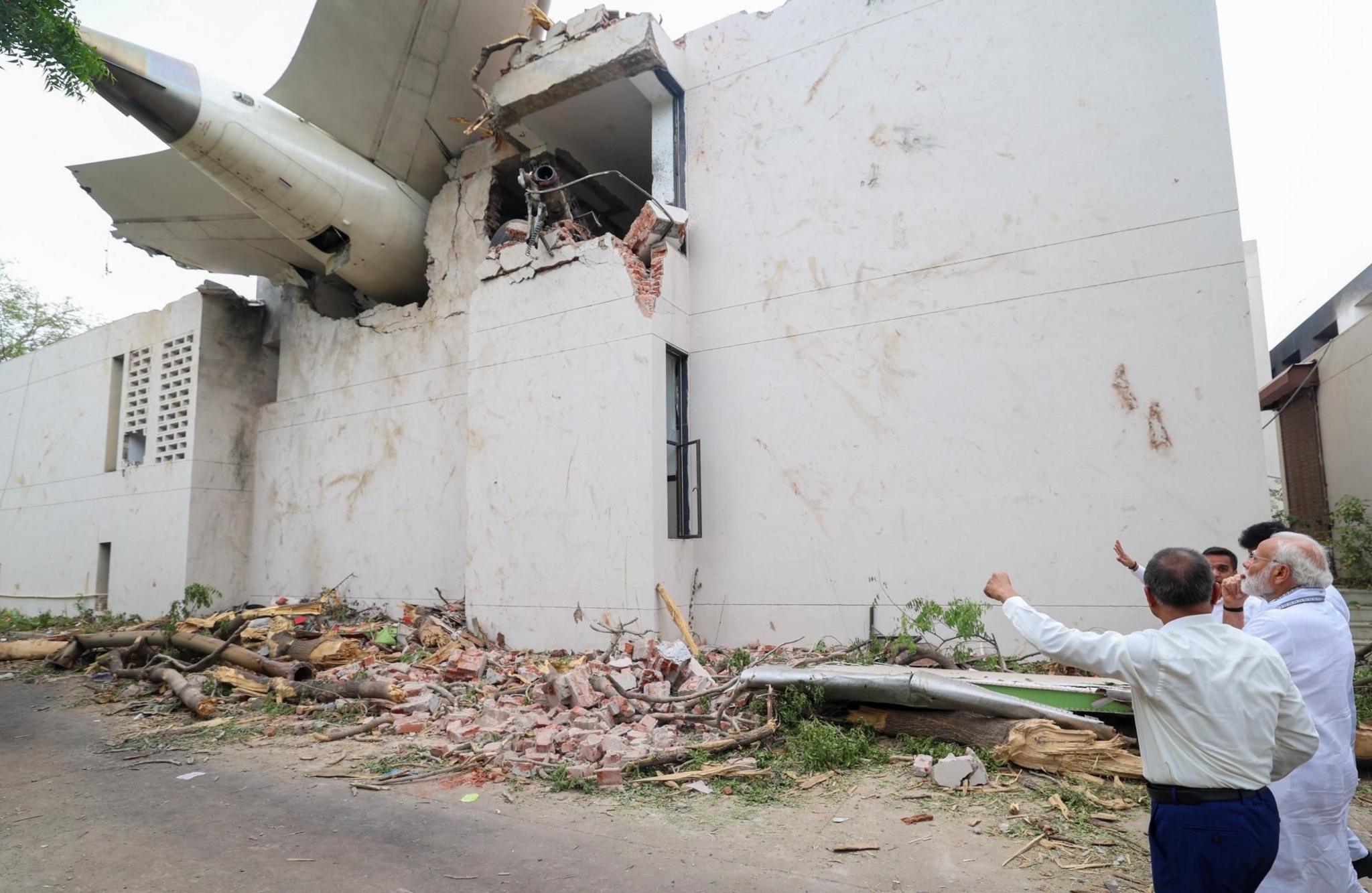 Narendra Modi looking up at the plane's tail that is crashed into a building.