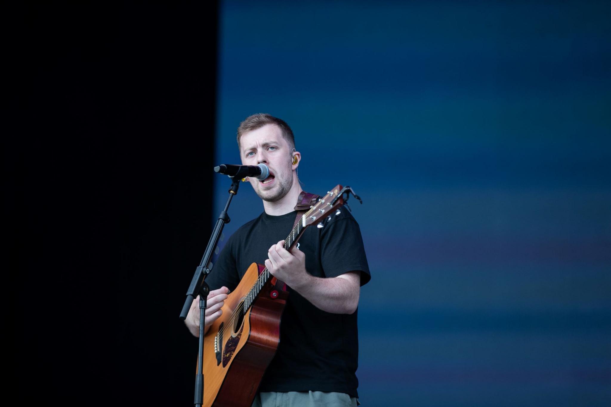 Man with guitar singing into microphone