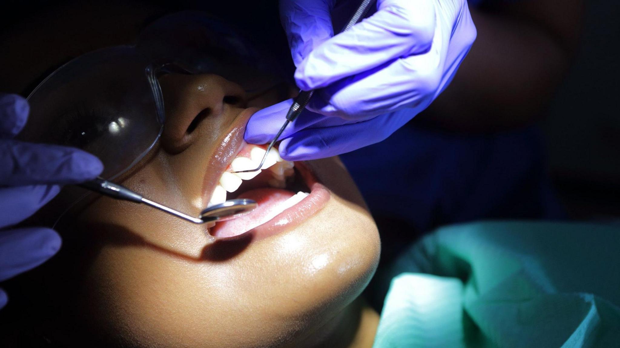 Woman lying down having dental treatment under a bright light