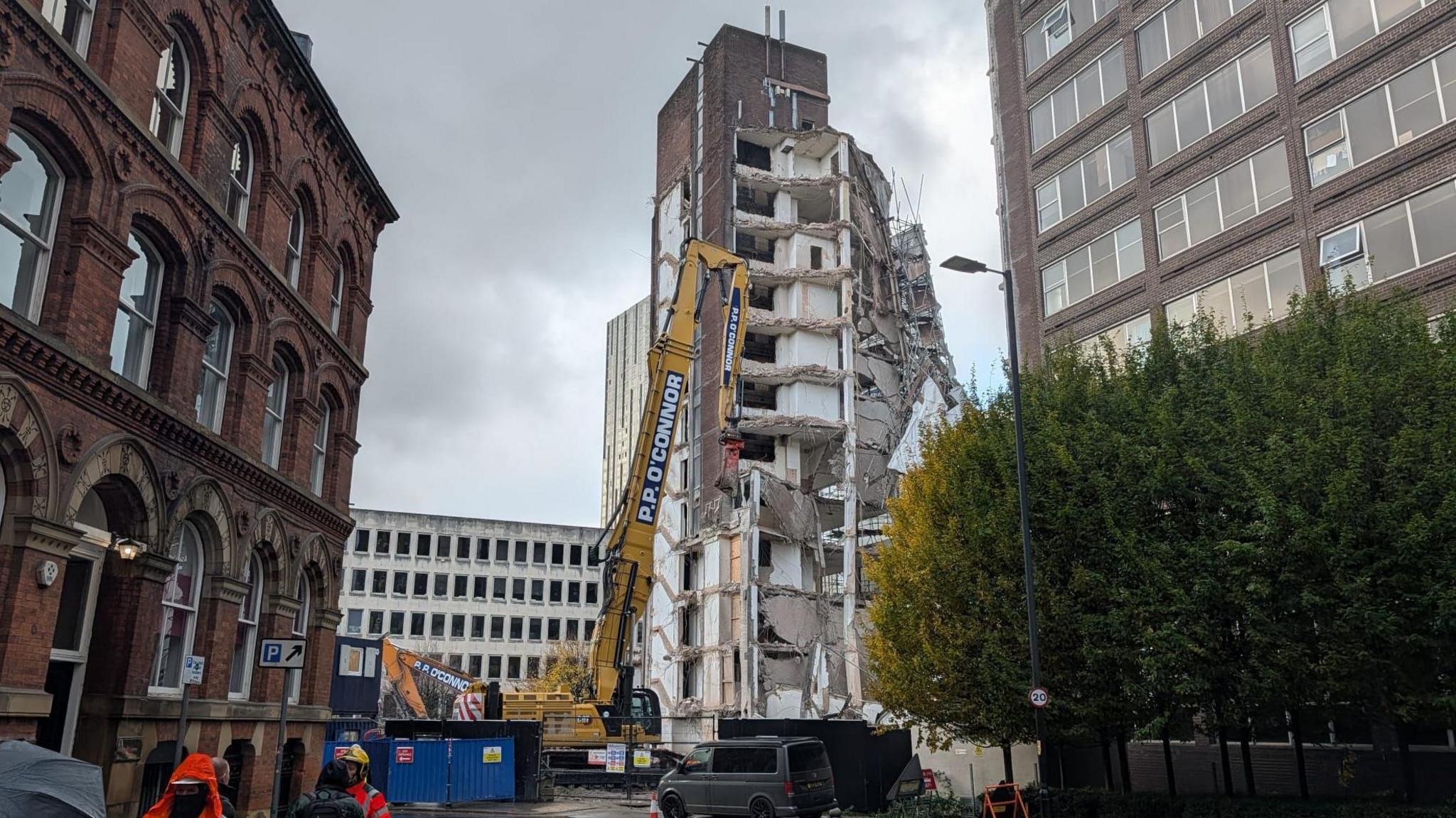 The building is collapsed on one side with construction vehicles around it