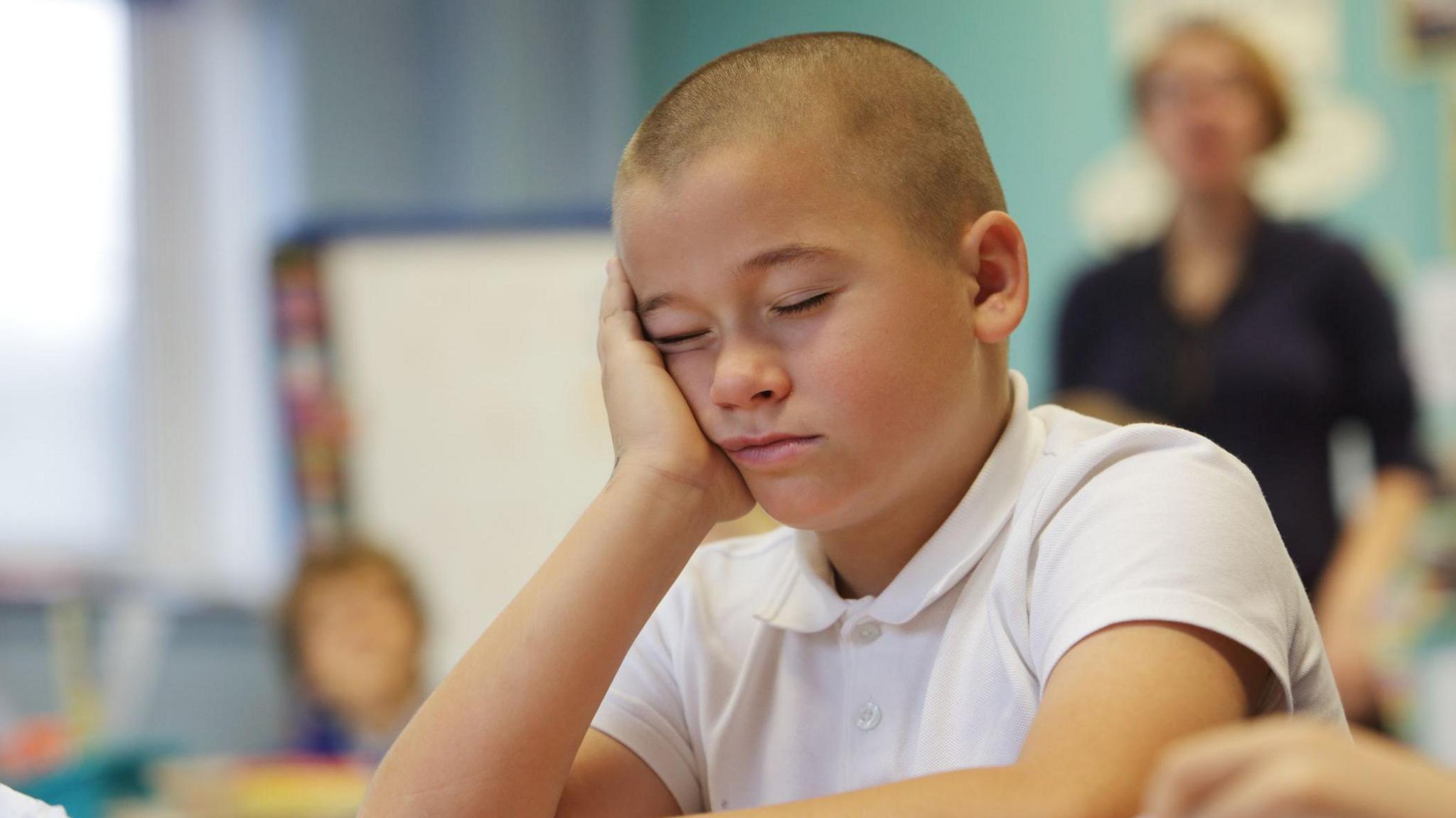 A school pupil falls asleep in his classroom