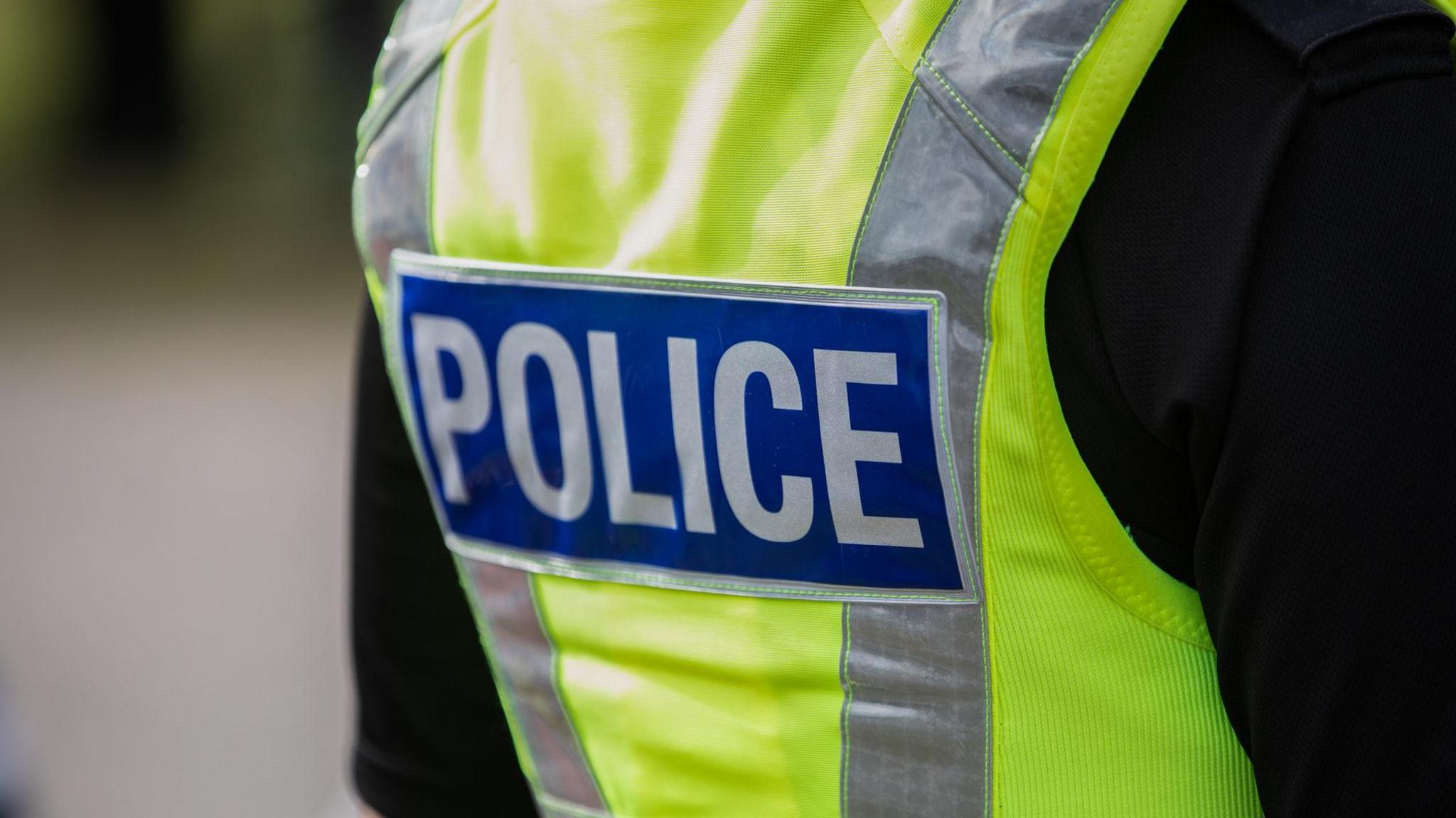 A close up of a police officer wearing a high vis police vest