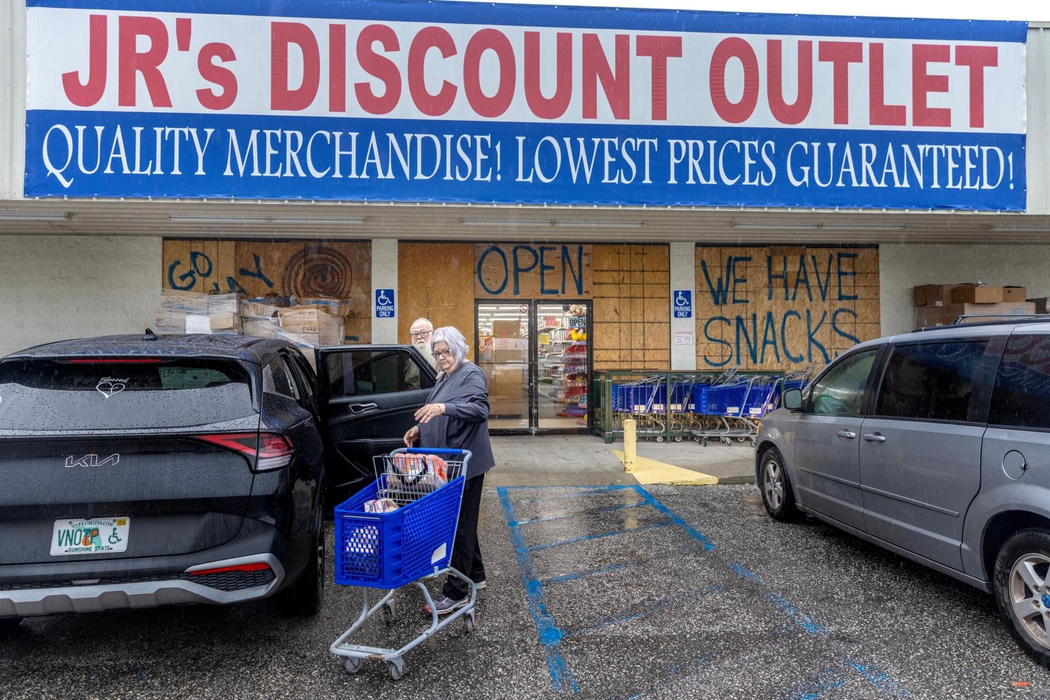 People buying groceries at a convenience store with windows covered with plywood as the town prepares for Hurricane Helene, in Old Town, Florida 
