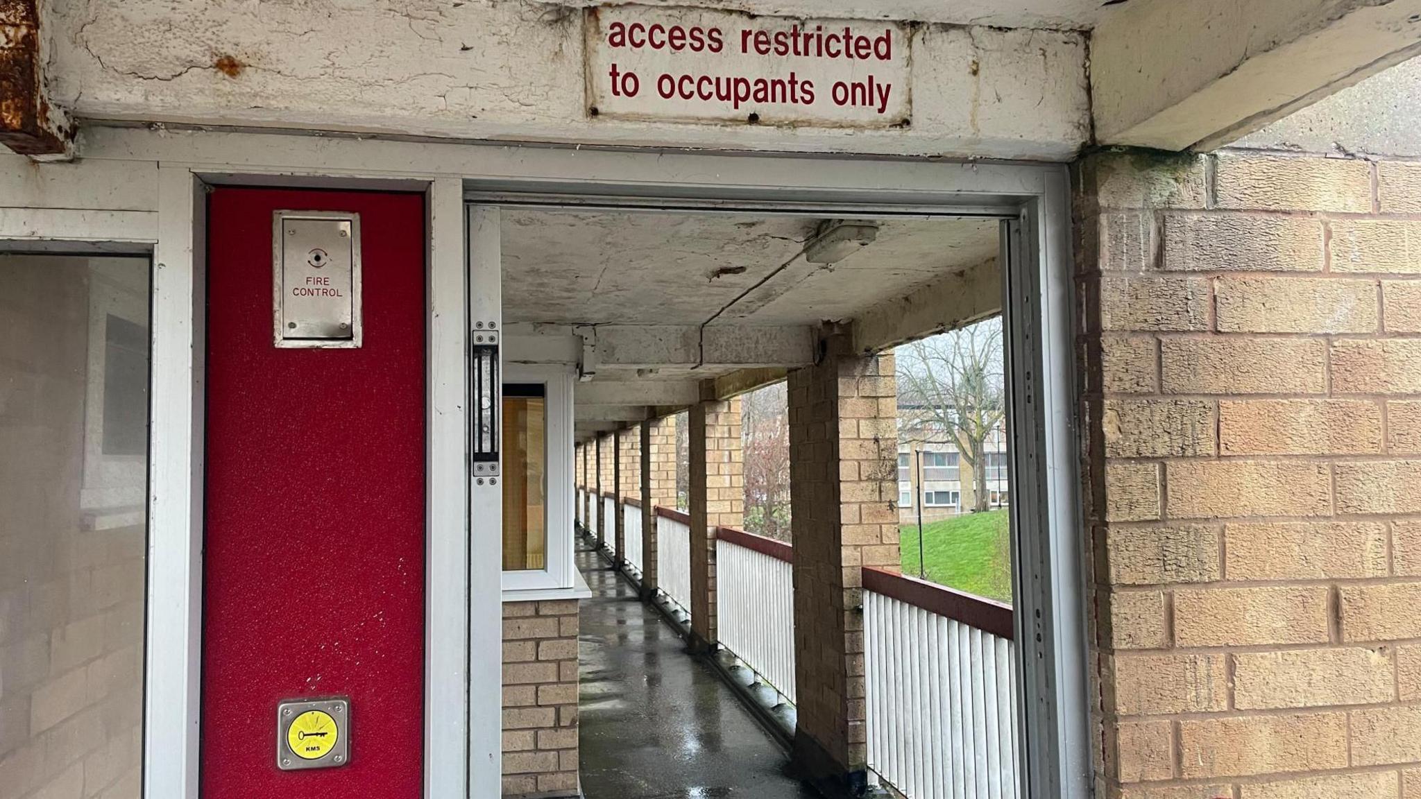 An empty doorway leading to a corridor in a block of flats.