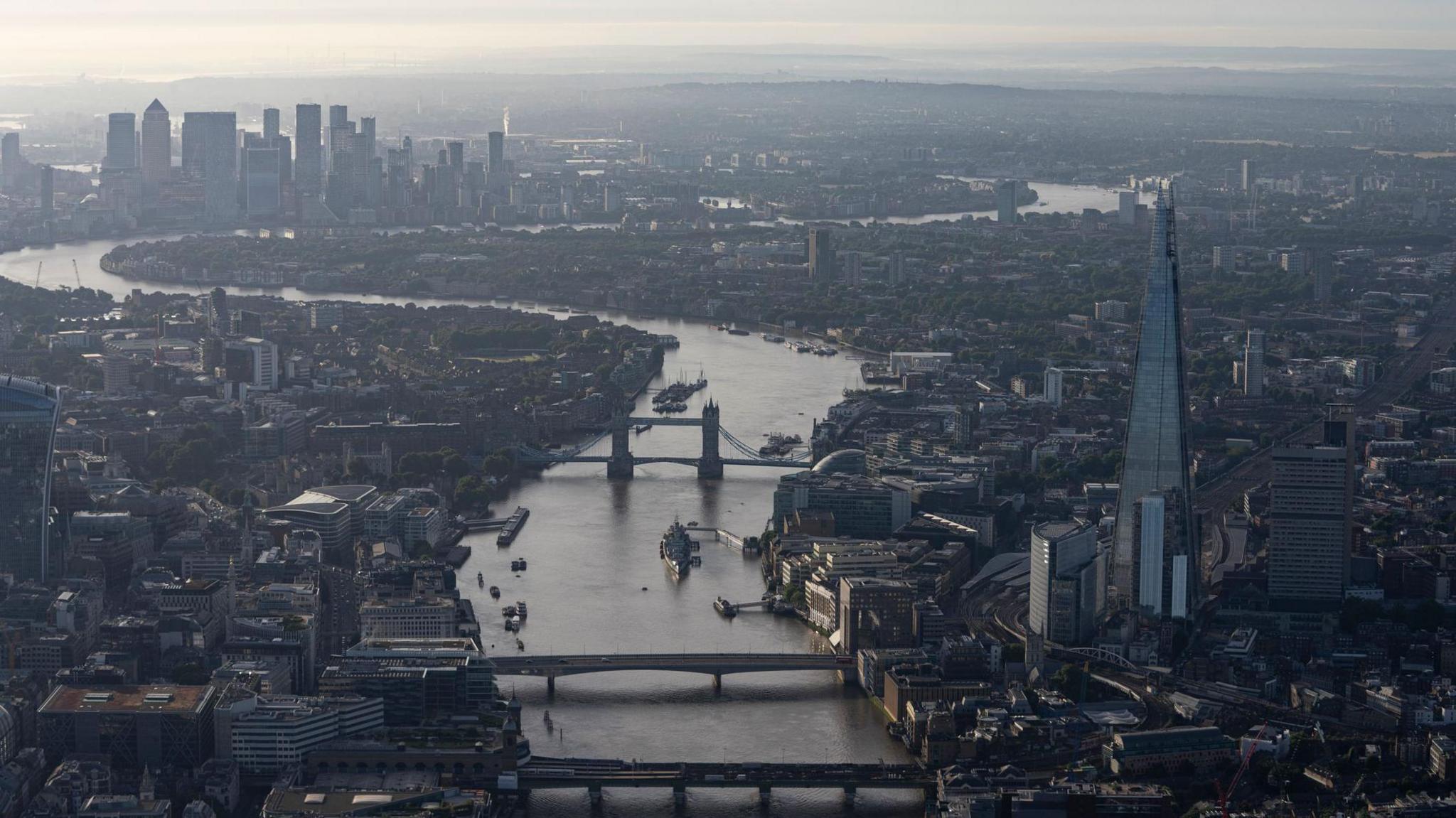 The skyline of London at dawn facing towards Canary Wharf's skyscrapers. There are several bridges in the foreground and the Shard is to the right of the image. 
