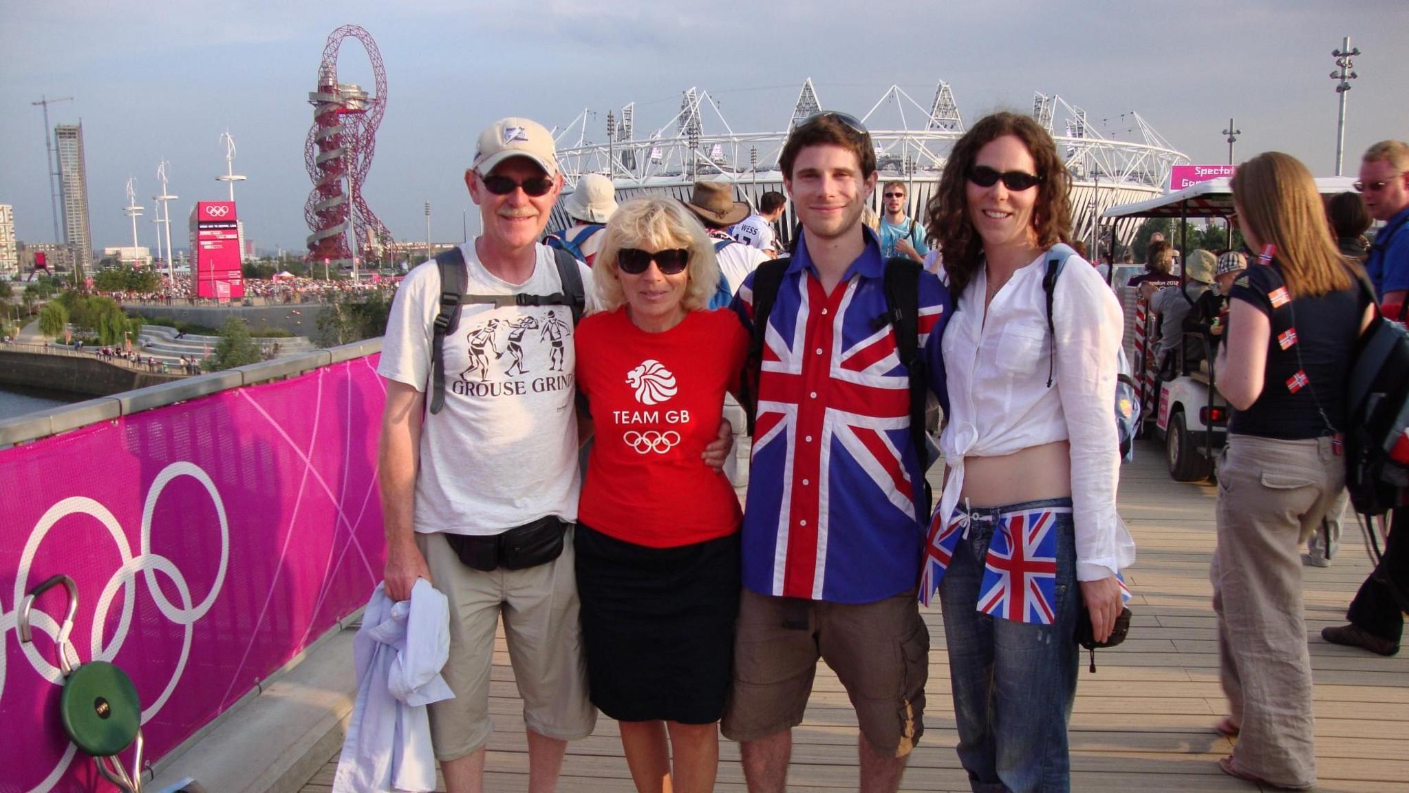 Julia Beeden with her family before being diagnosed with breast cancer. They are standing outside the Olympic Stadium during London 2012. Julia is wearing a white shirt and has sunglasses on, her brother is wearing a shirt with a union jack on it, while her mother is wearing a red Team GB T-Shirt and her father has a cream T-shirt with a back pack and bum-bag.