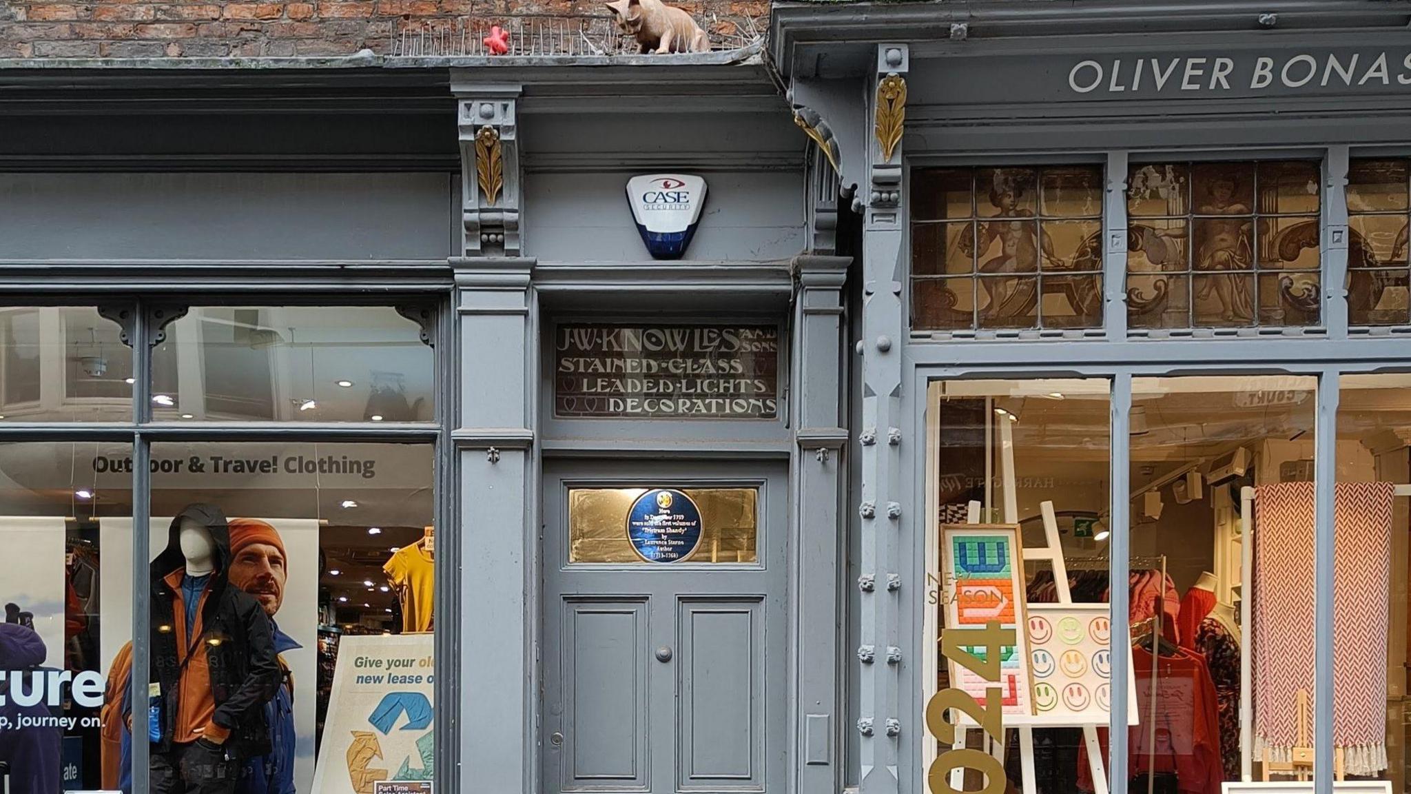 An image of the shop door above which is the stained glass blue plaque