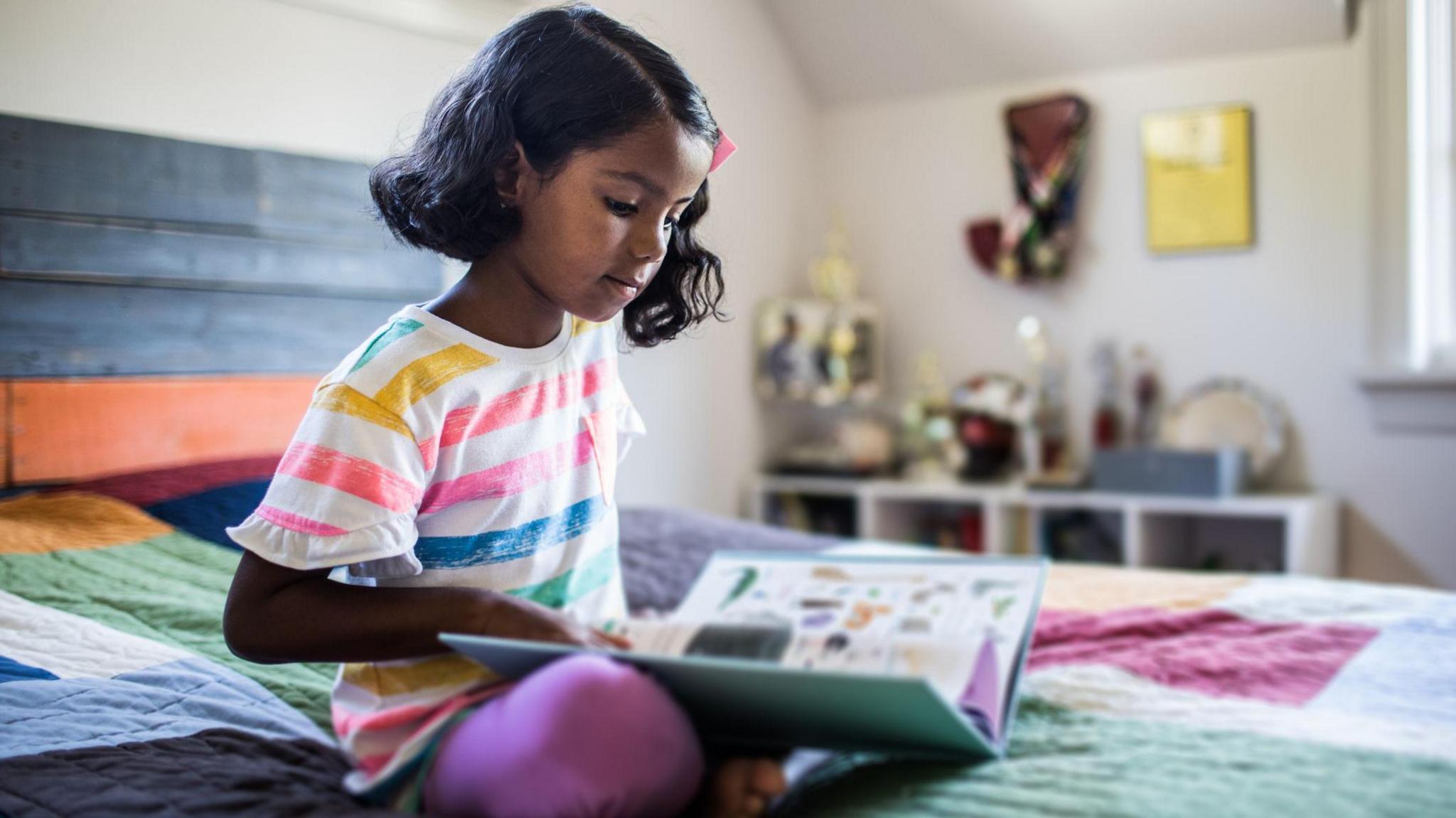 little girl reading a book in her bedroom