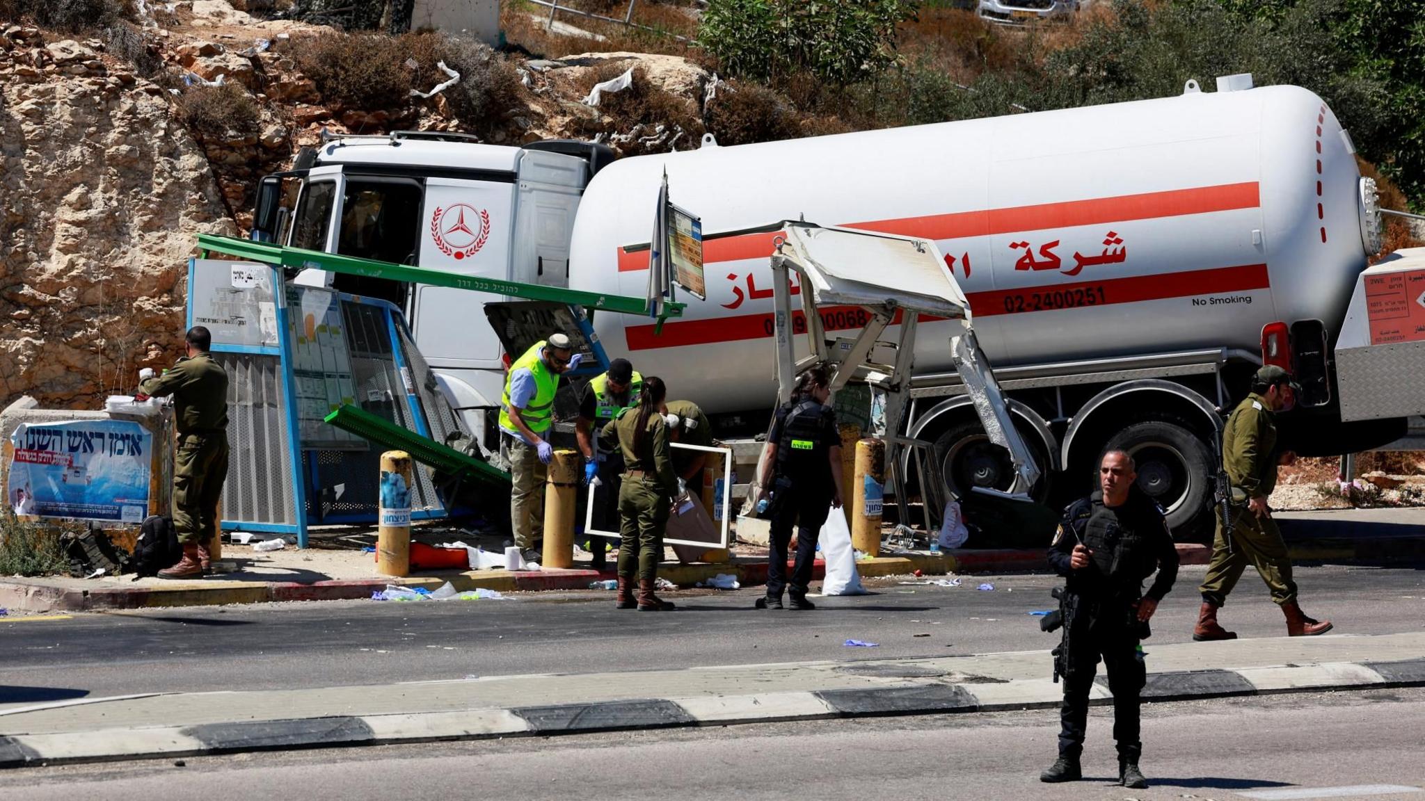 Israeli security and emergency personnel work at the scene of what the Israeli military said was a tanker ramming attack near the settler outpost of Givat Assaf, in the occupied West Bank (11 September 2024)