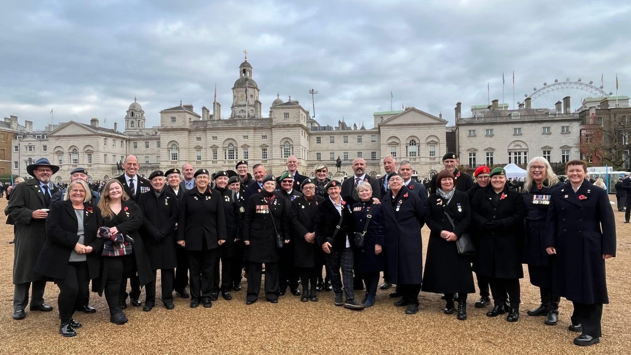 A group of several dozen men and women, some wearing military berets and medals. 