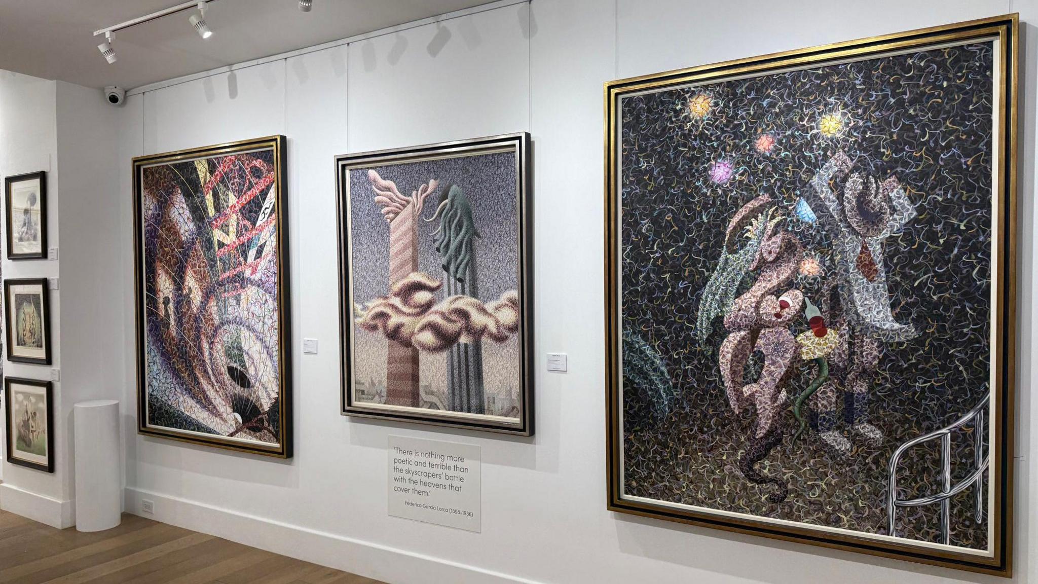 A white wall with large surrealist paintings by Henry Orlik hanging up. 