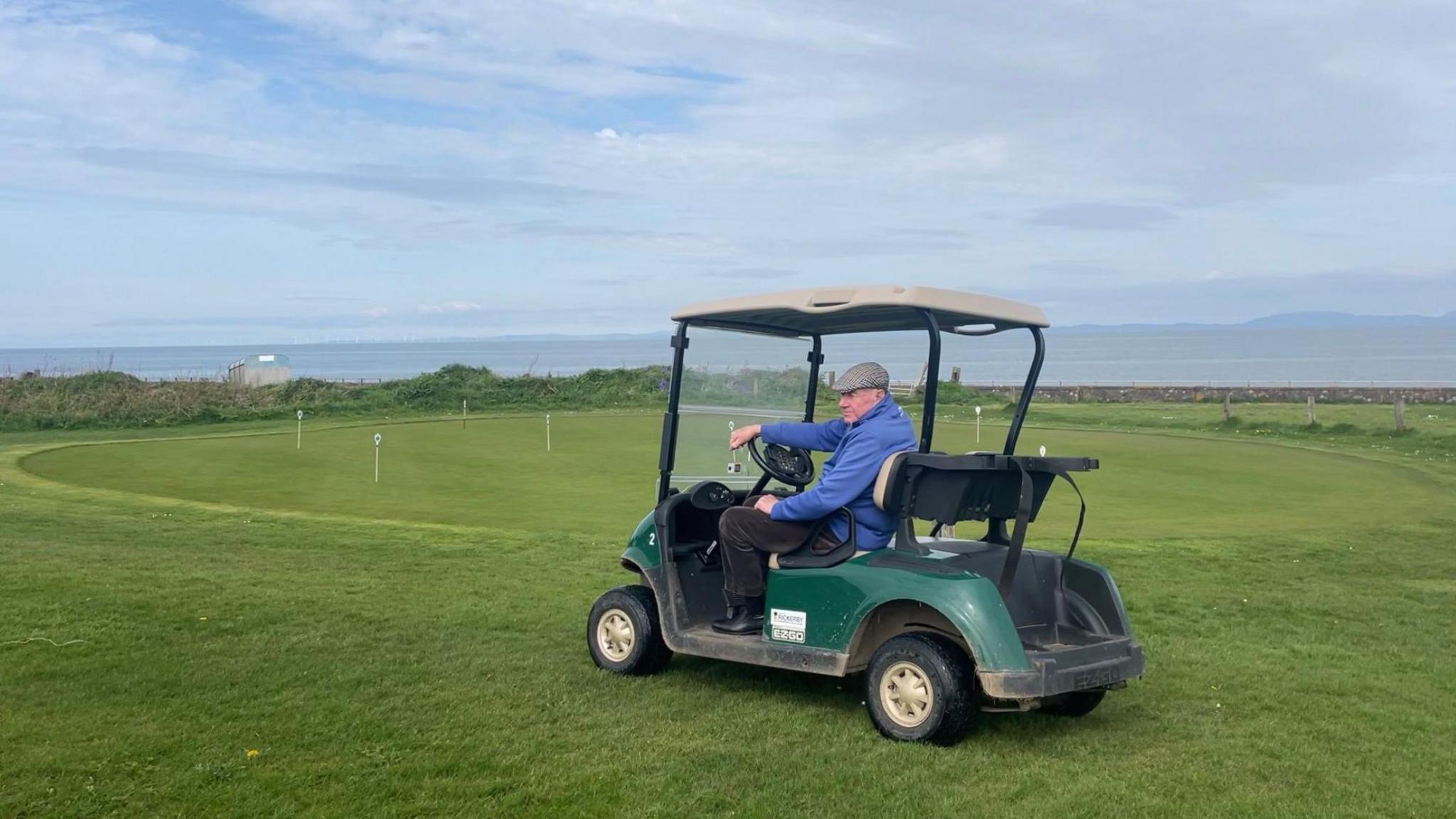 Man sat on golf buggy on putting green