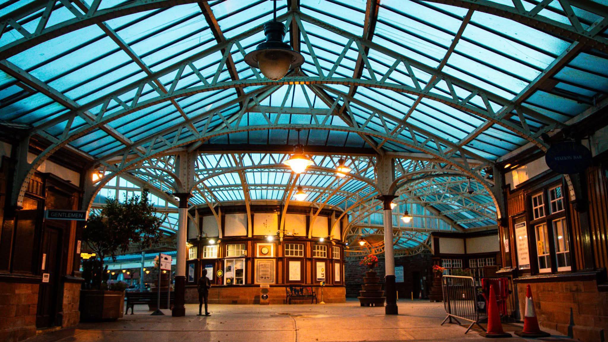 A railway station with a glass roof and vintage wooden ticket booths.