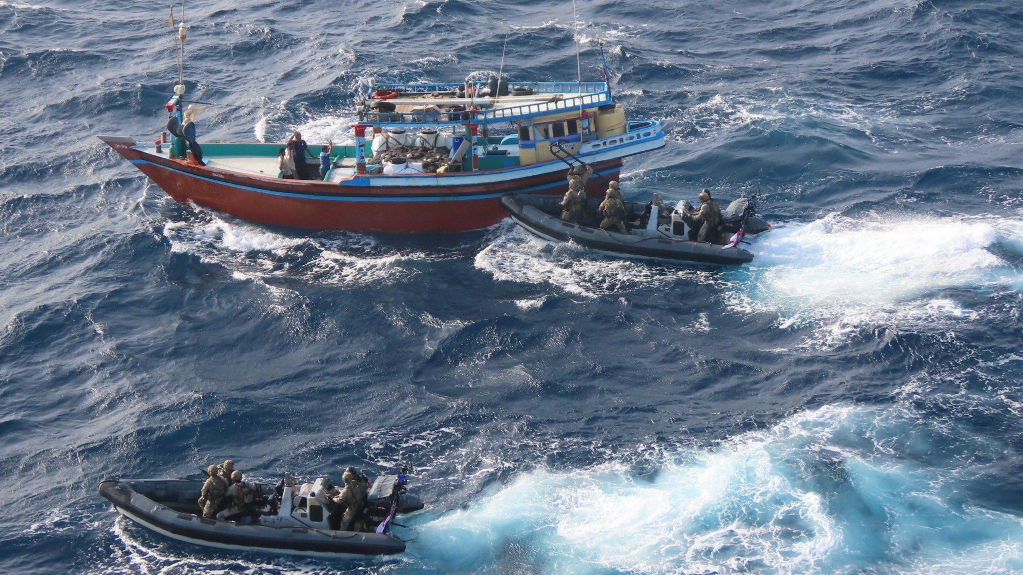 Two royal marine ribs chasing down a small sailing boat in the sea.
