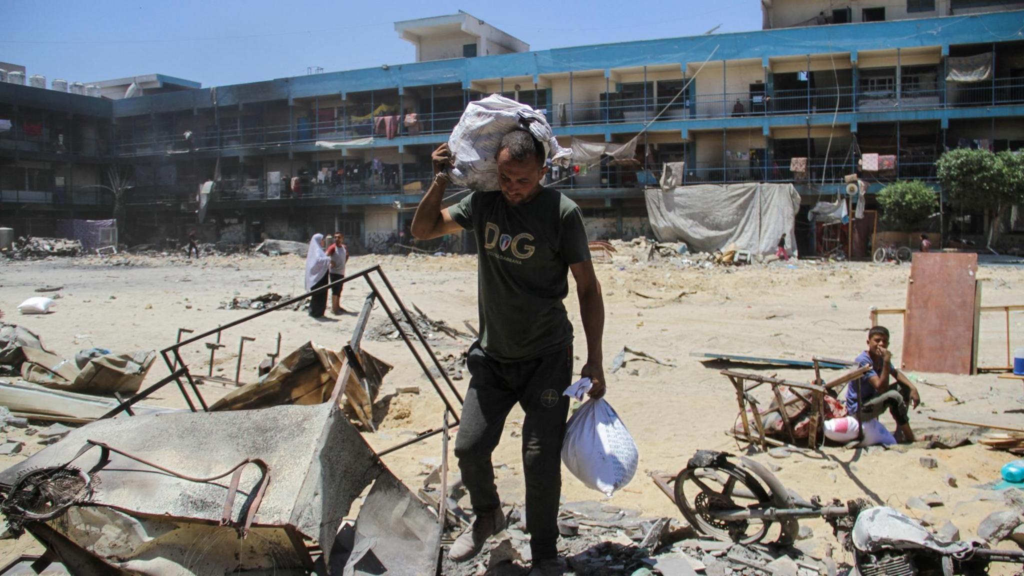 Palestinian man Bilal Khrouat carries his belongings to a shelter inside an Unrwa school in Jabalia, in the northern Gaza Strip (2 June 2024)