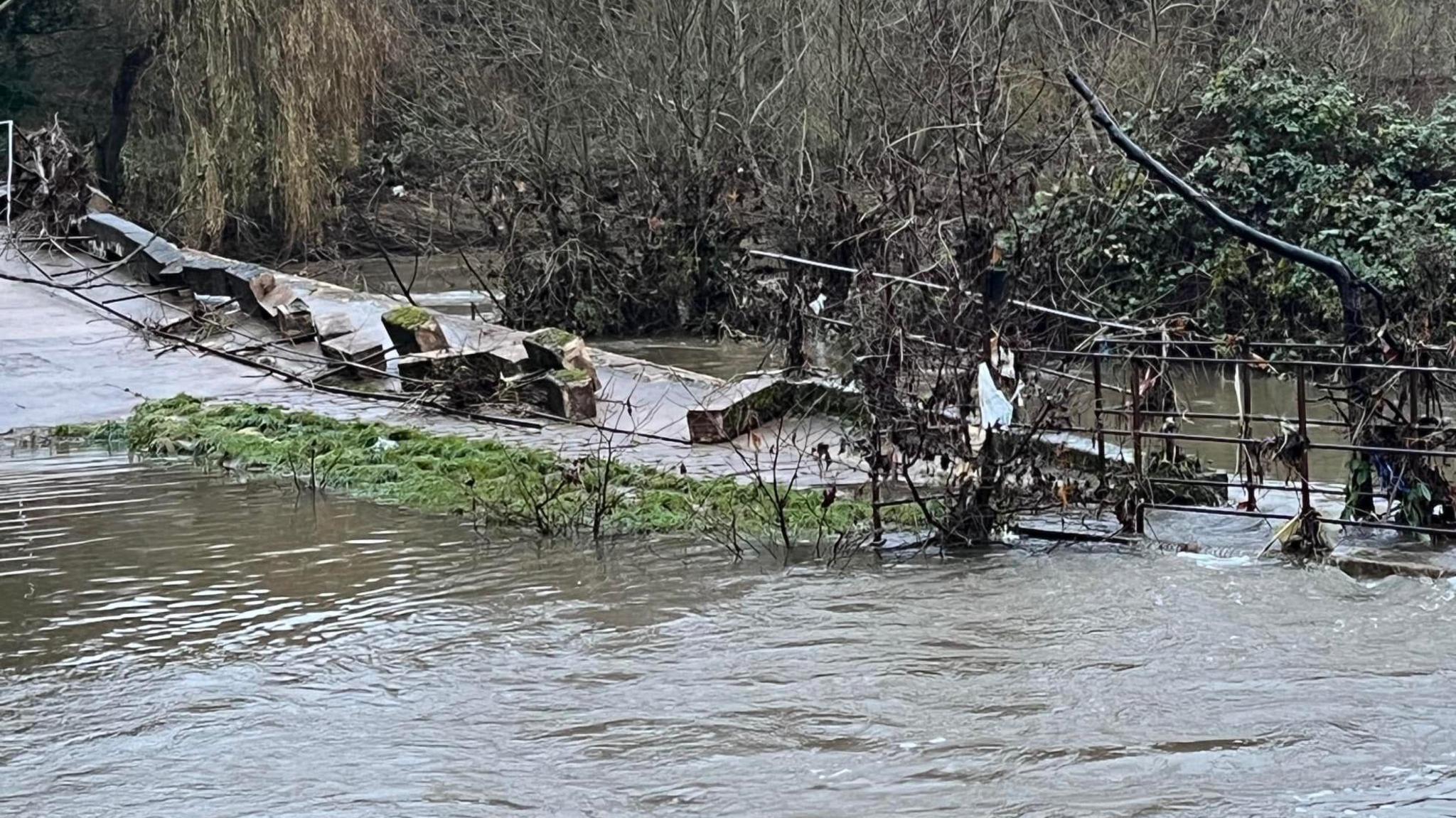 A flooded Pack Bridge in Bradford-on-Avon, with loose debris to one side.