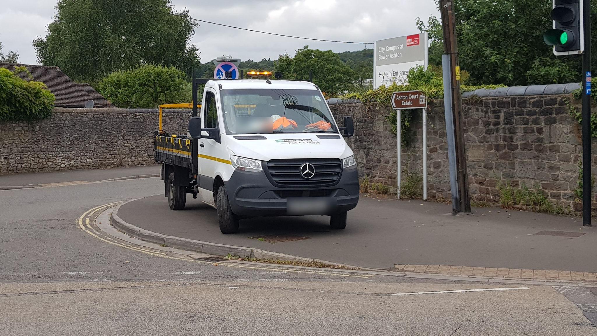 A white pick up truck with orange hi-vis tops in the window fully parked on a pavement