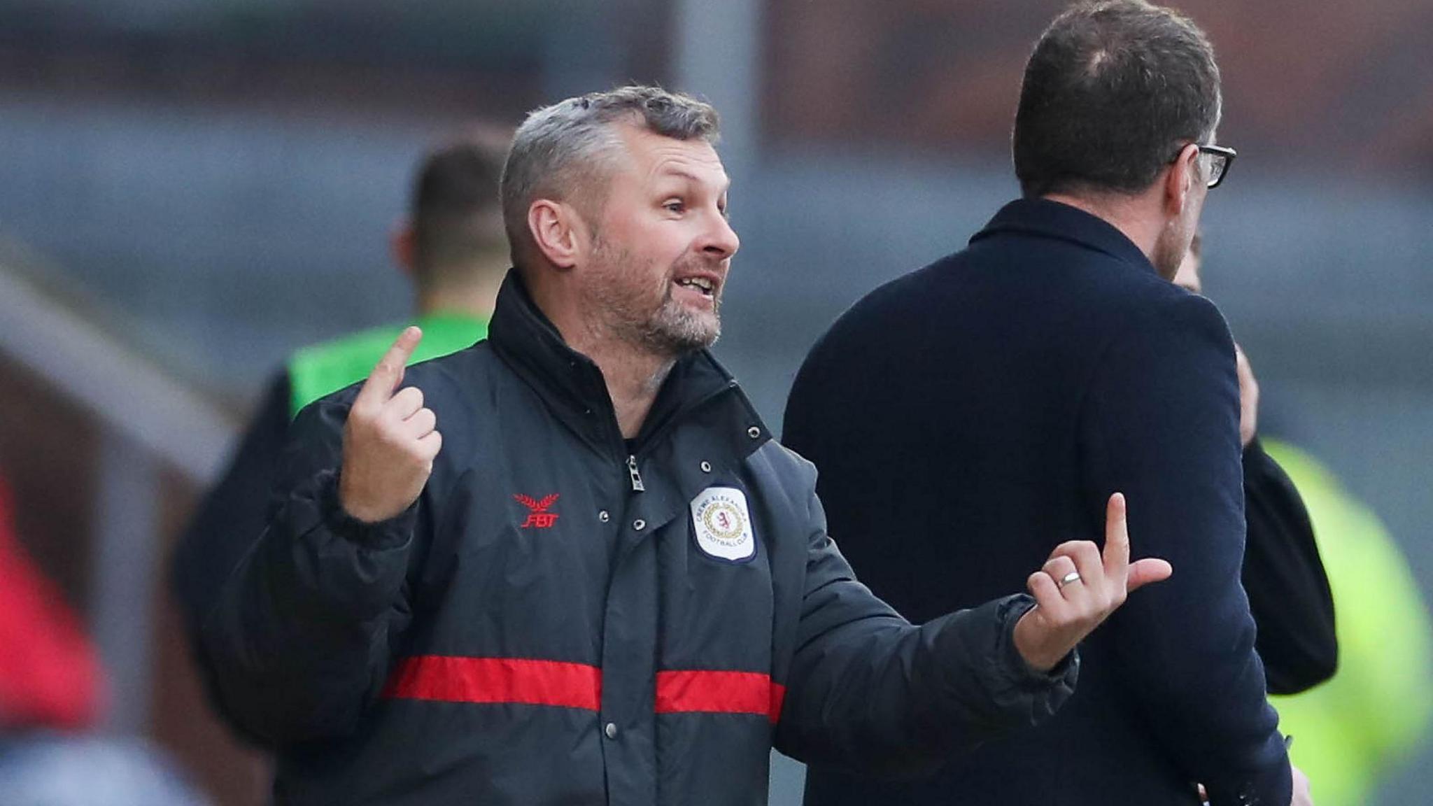 Kenny Lunt is on the touchline pointing at the Crewe players during a match