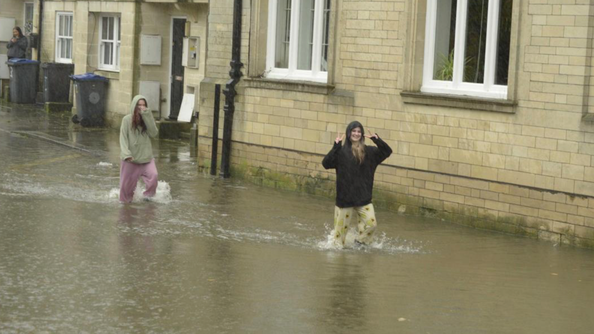 Two girls wading in water after flooding in Calne with the water up to above their ankles