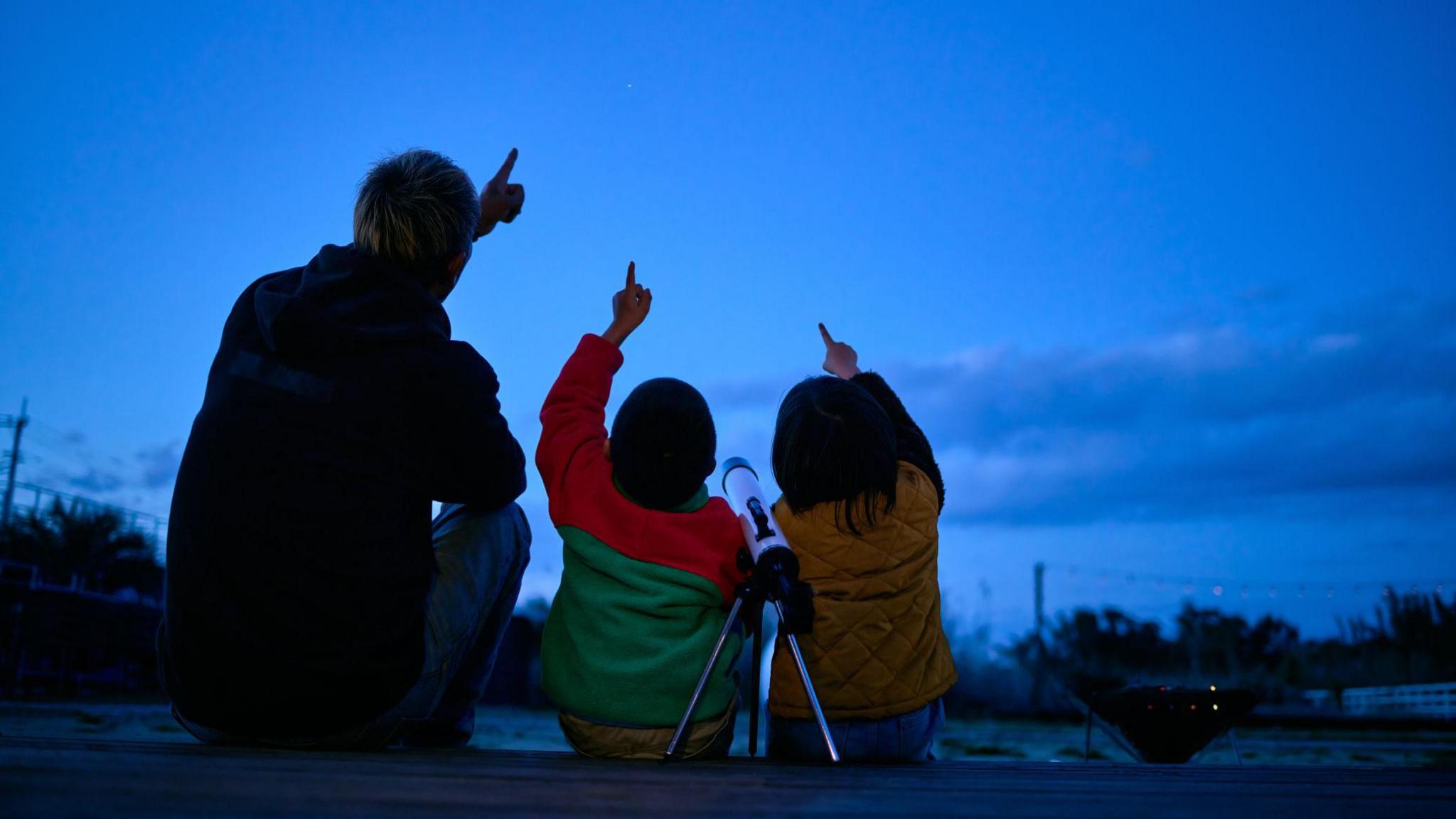 people looking up at the sky and pointing.