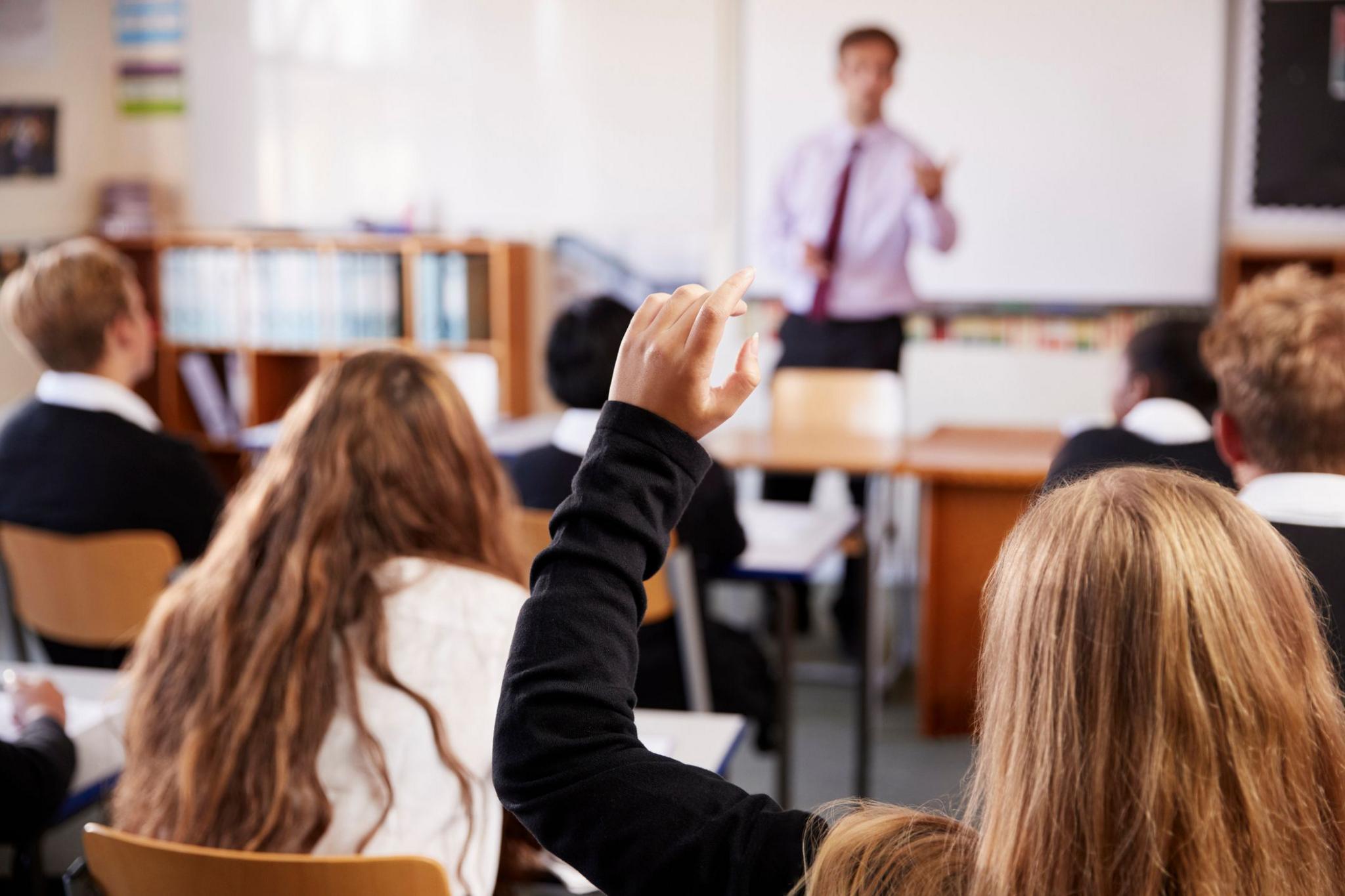 Children with their hands up in a classroom