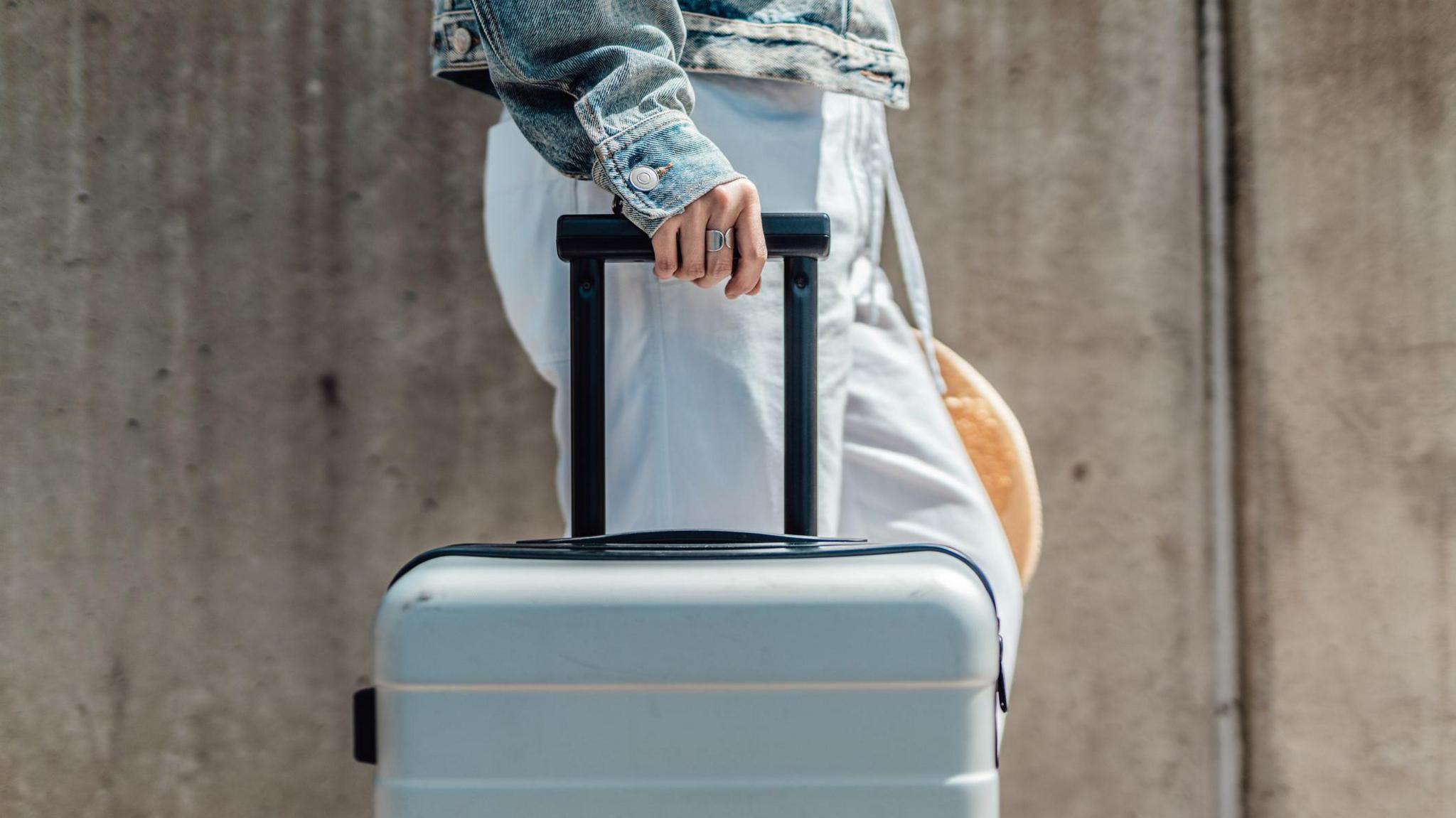 Cropped shot of young woman with suitcase walking