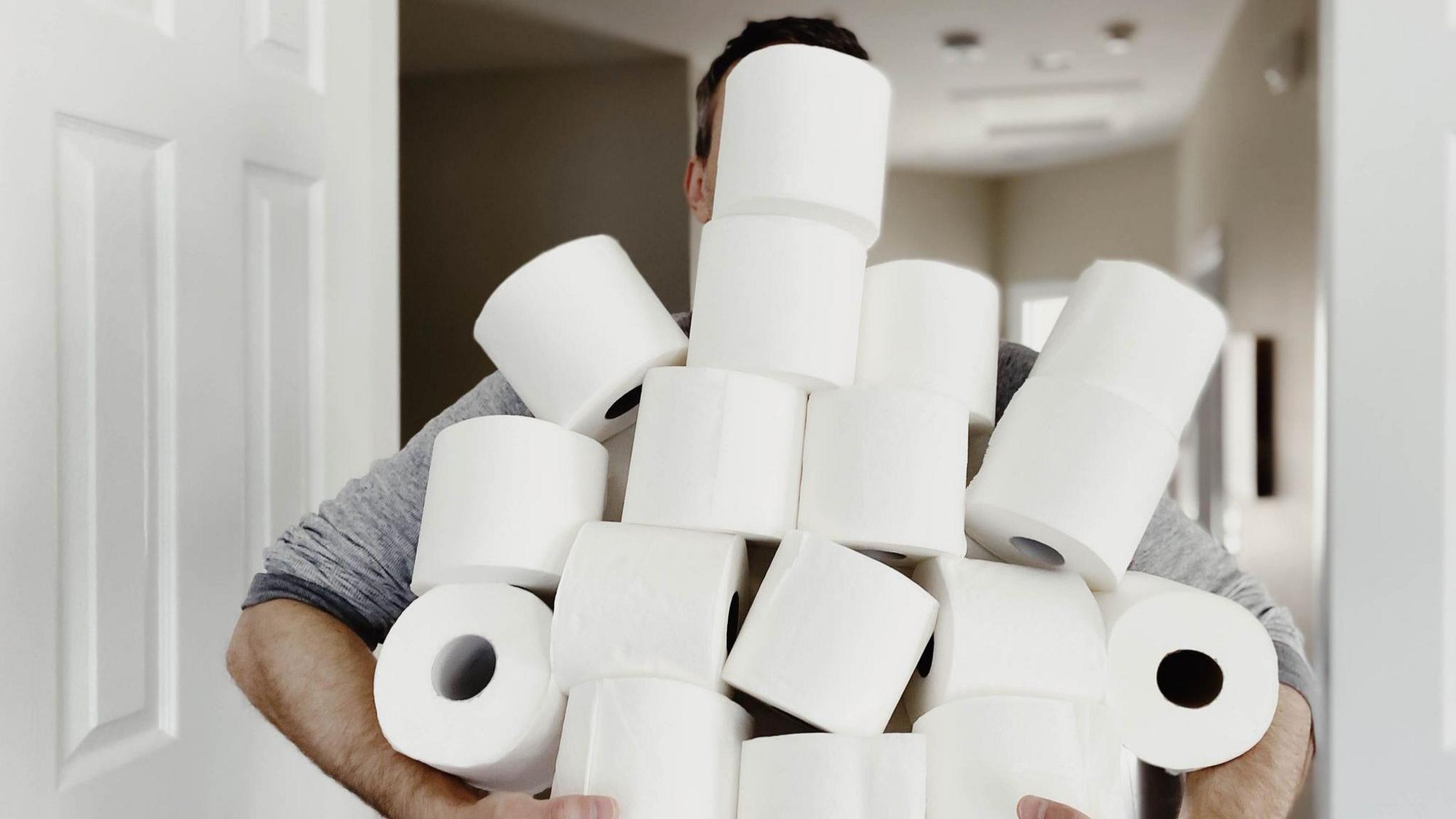 Close-up of unrecognizable man carrying an abundance of toilet paper.