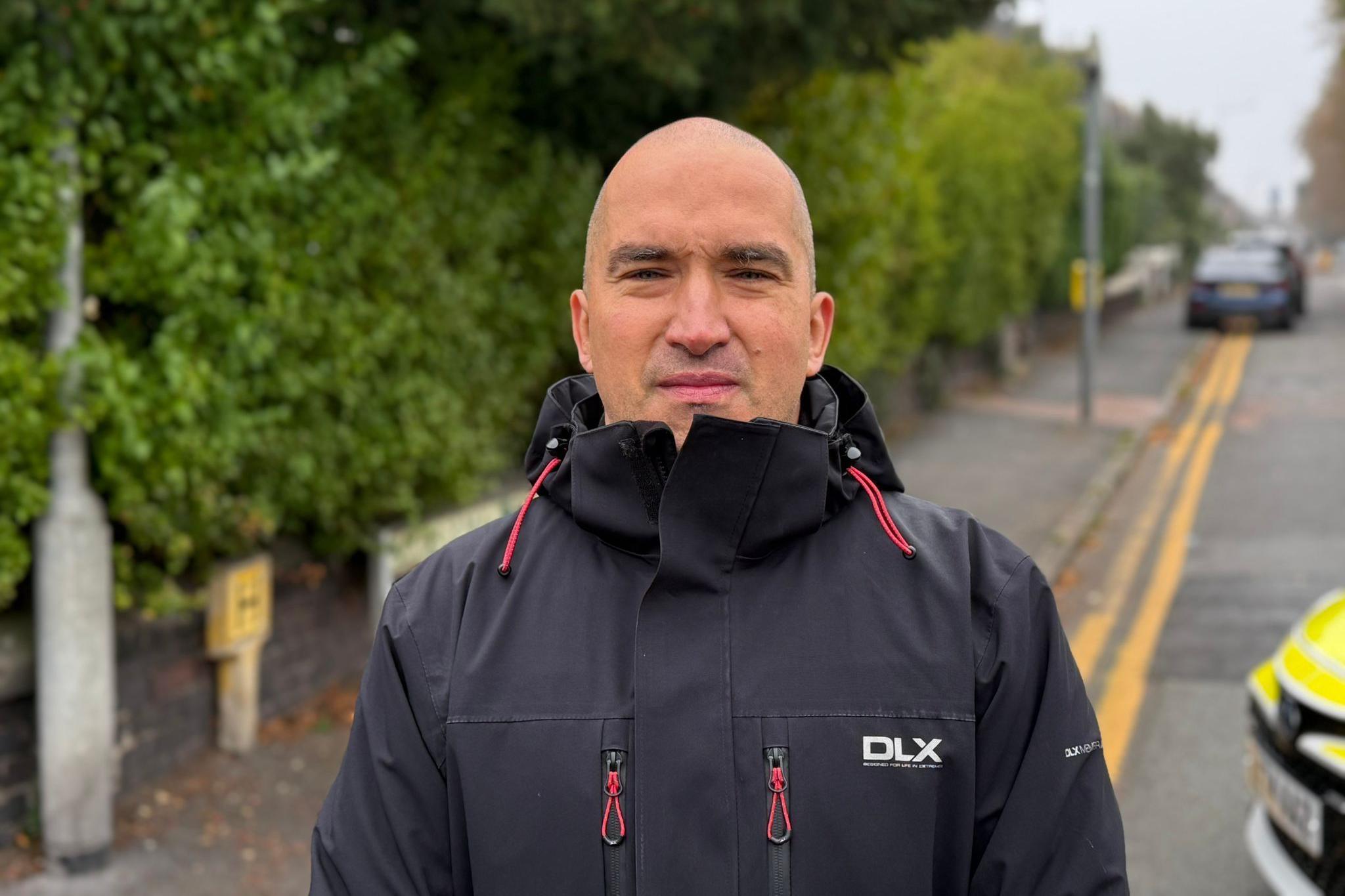 Sebastian Grzesiak has a closely shaved head and is wearing a dark waterproof with red embelishments.  