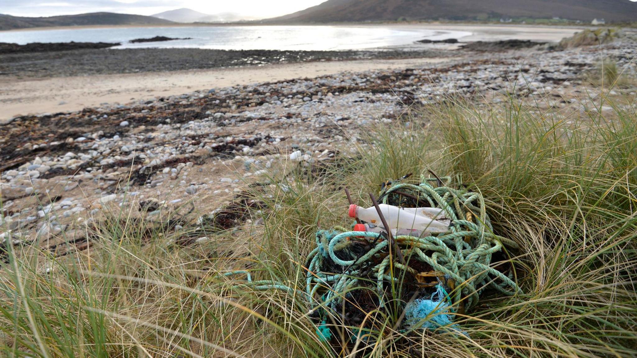 Plastic items and rope left on the beach. 