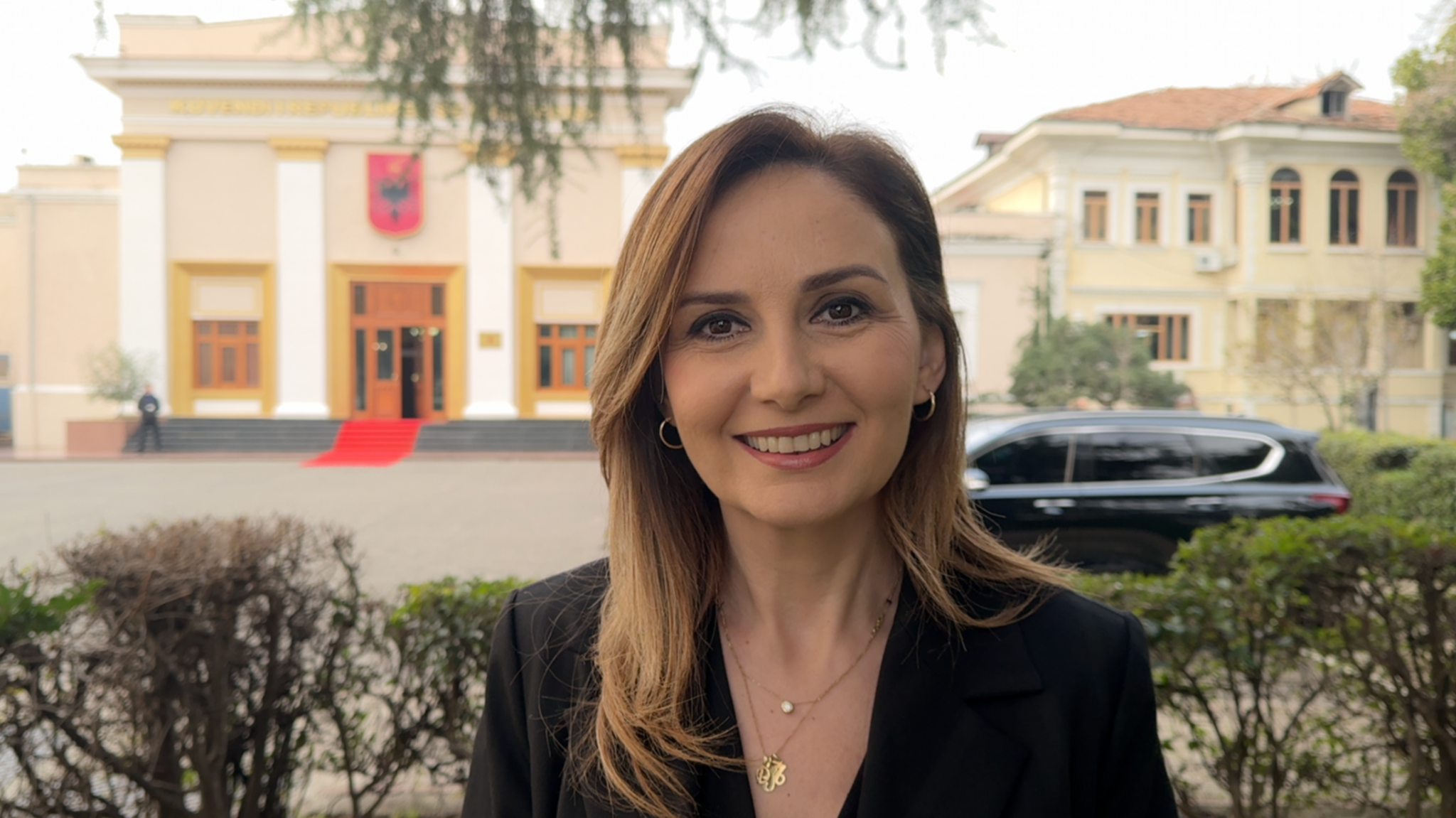 Jorida Tabaku, an  MP from the Democratic Party, is standing outside the Albanian Parliament building in Tirana.