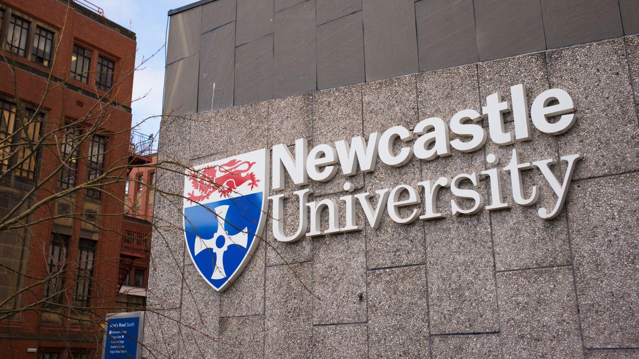 A Newcastle University logo on the side of one of its buildings.
